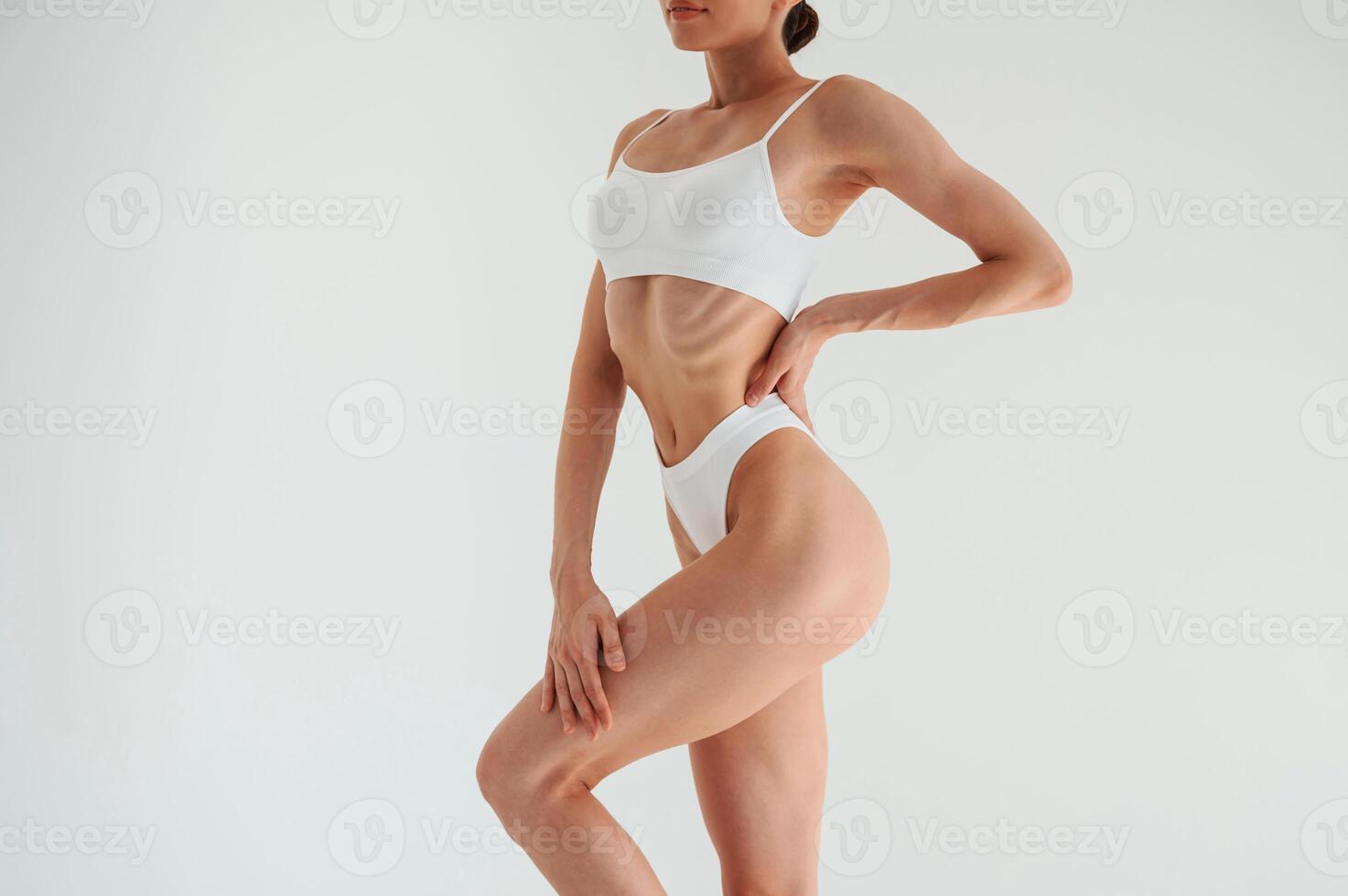 Slim body type.. Woman in, white underwear is standing against white background photo