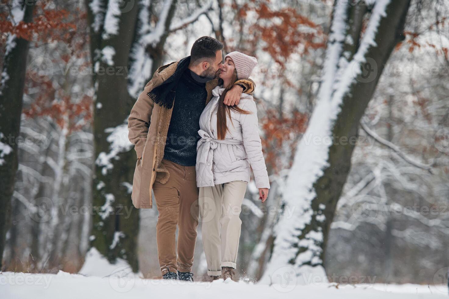 Lovely couple have a walk in the winter forest photo