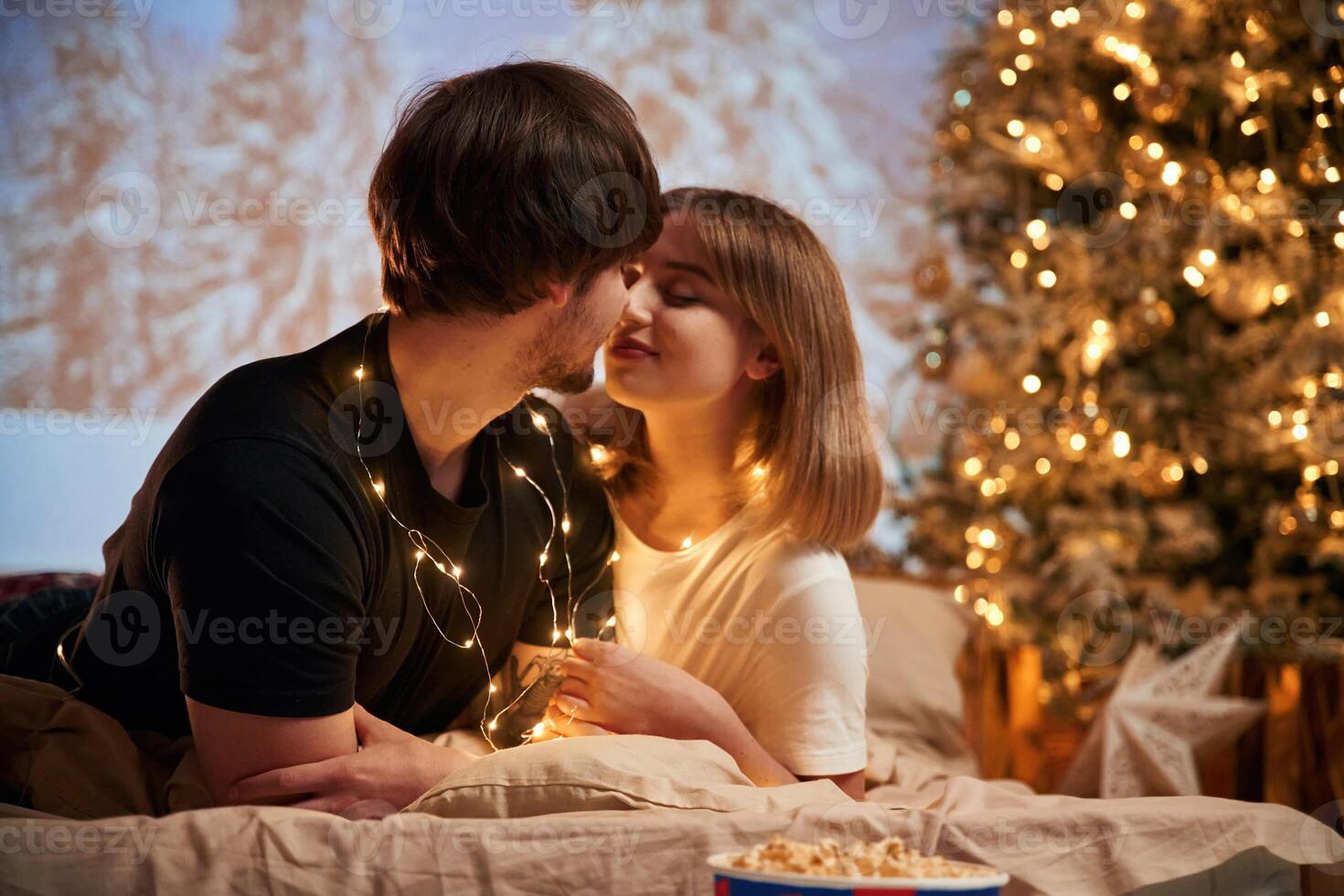 Closeness ,of the people. Beautiful young couple indoors, celebrating new year against projector photo