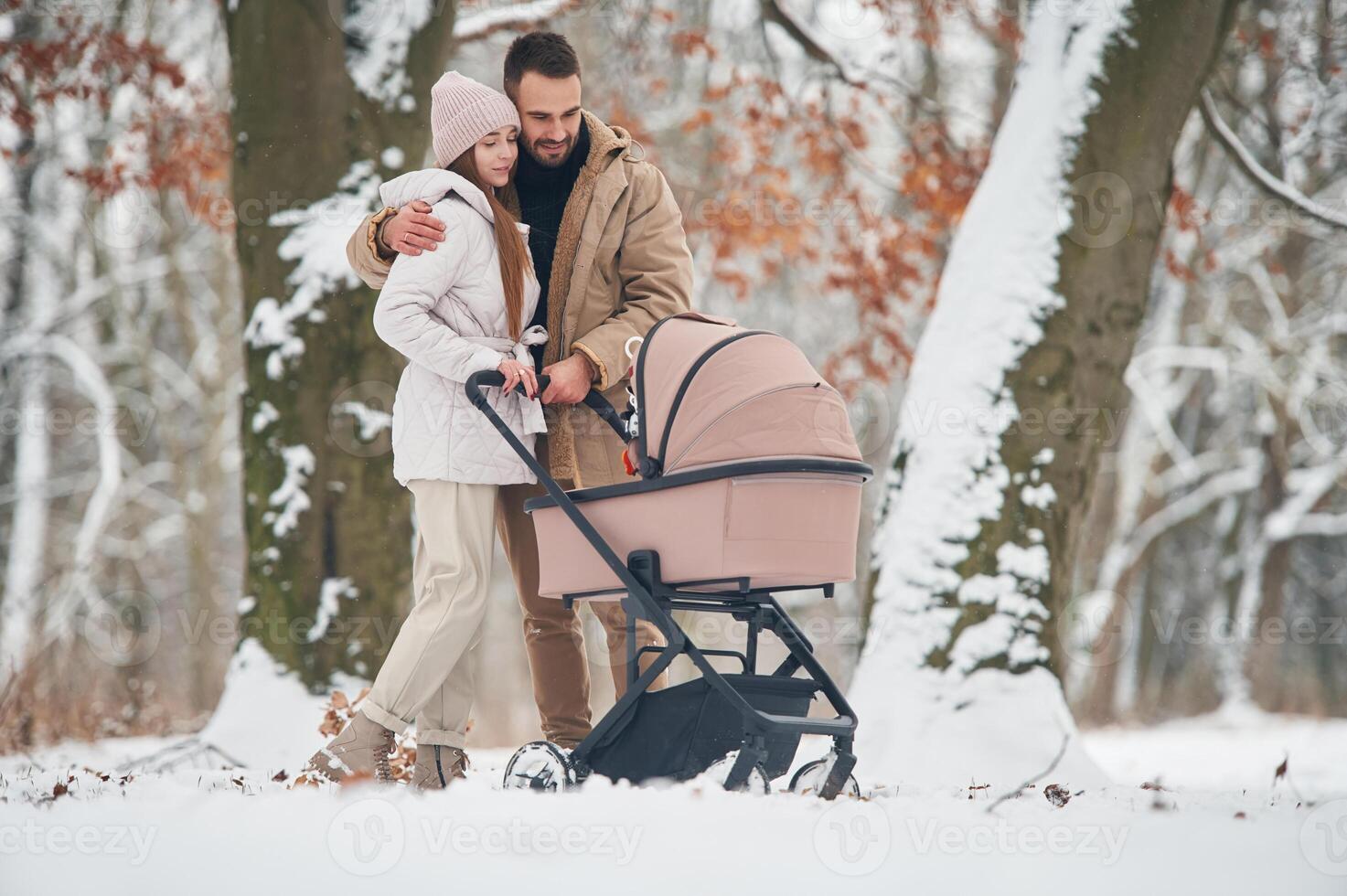 Mother and, father, with pram.. Lovely couple have a walk in the winter forest photo