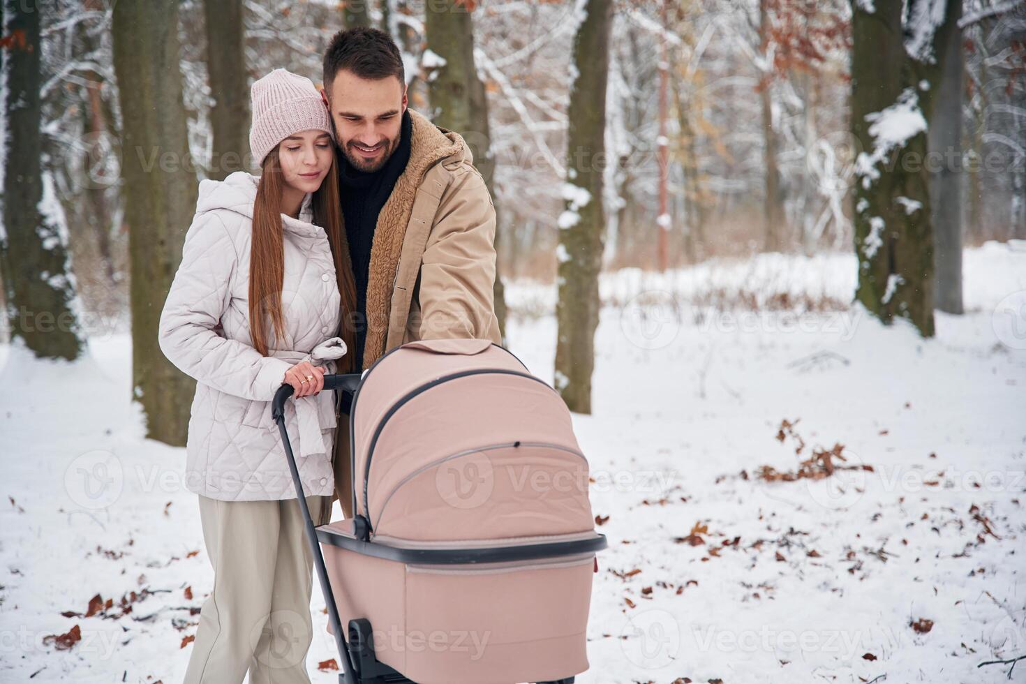 Parents with ,pram. Lovely couple have a walk in the winter forest photo