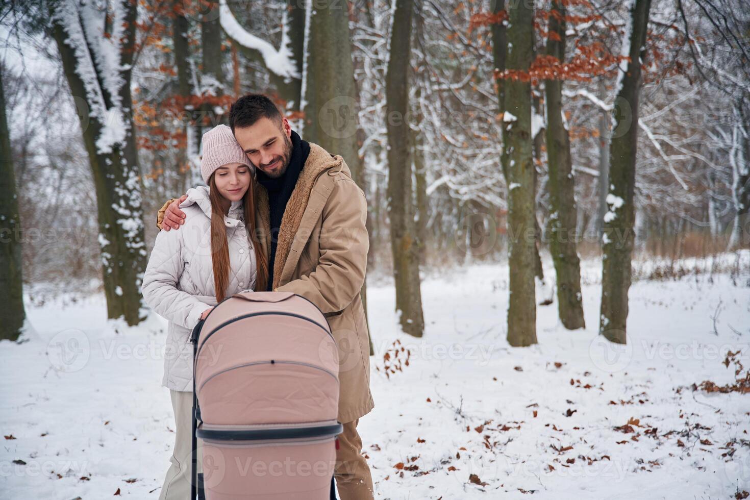 Mother, and father with pram. Lovely ,couple have a walk in the winter forest photo