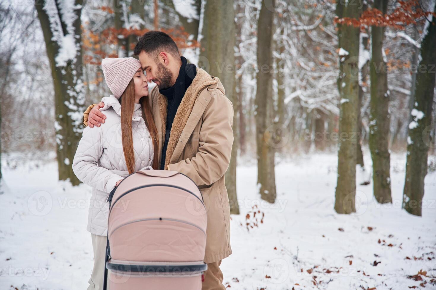 Parents with, pram. Lovely couple have a walk in the winter forest photo