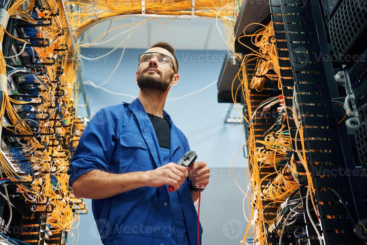 Handsome young man, is working, with internet equipment and wires in server room photo