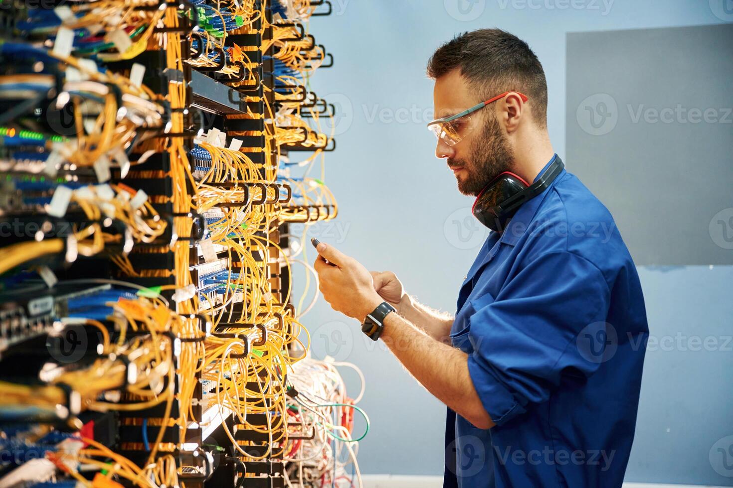 Side view. .Young man is working with, internet equipment and wires in server room photo