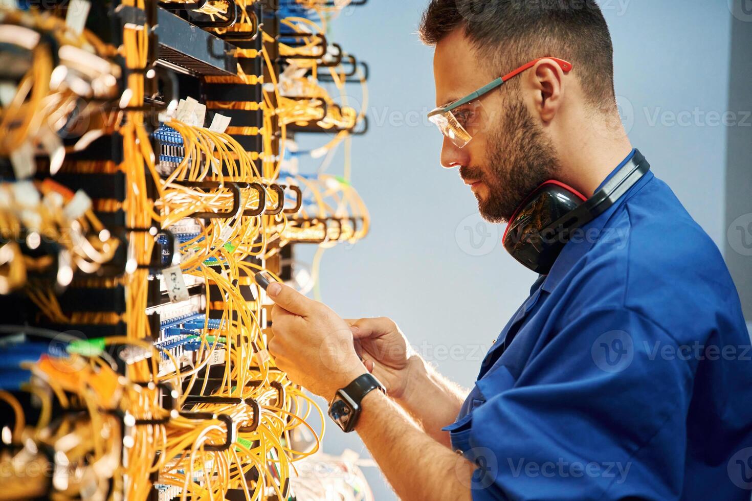 Side view. Young man is working with, internet equipment and wires in server room photo