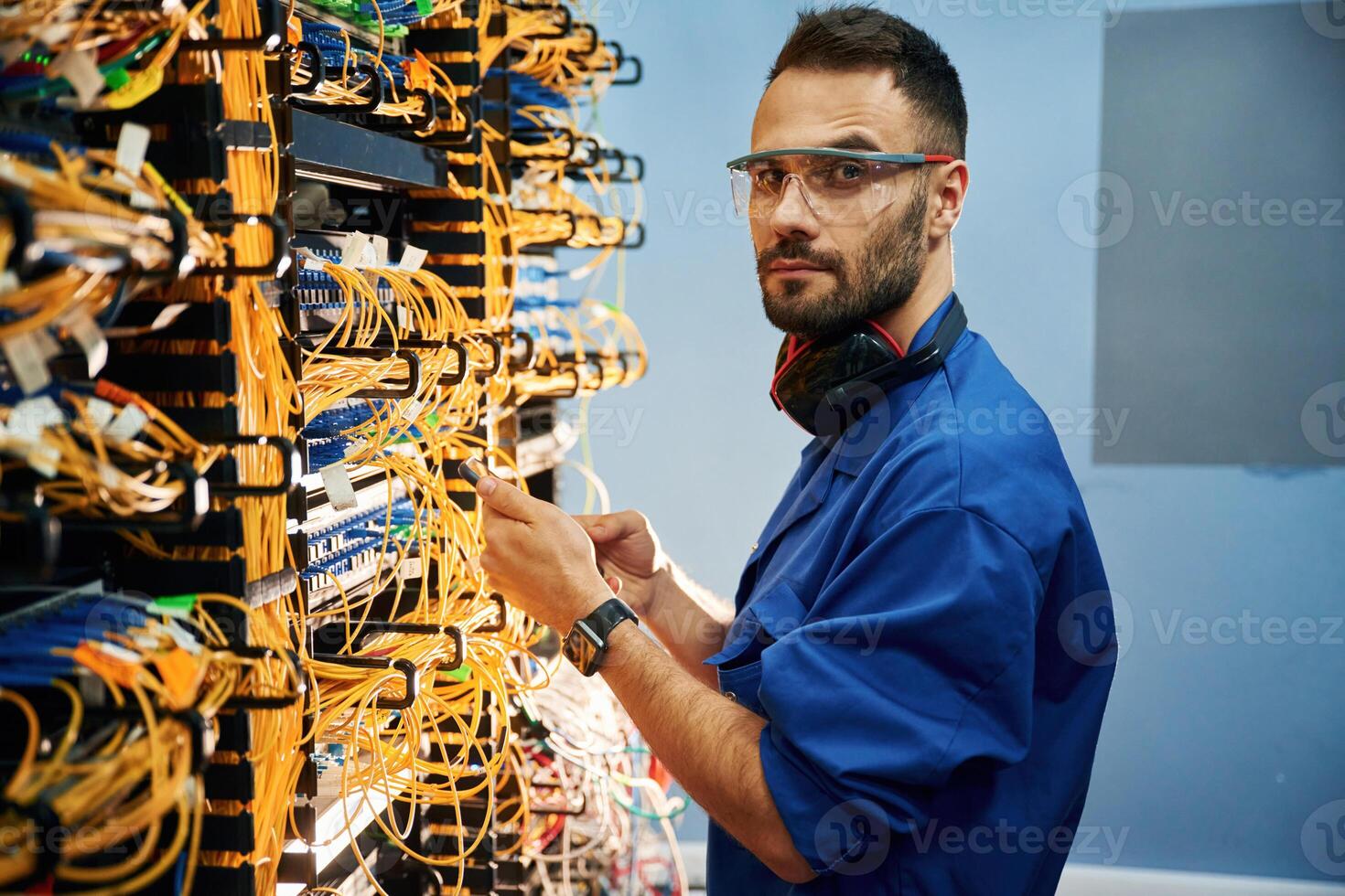 Side,, view. Young man is working with internet equipment and wires in server room photo