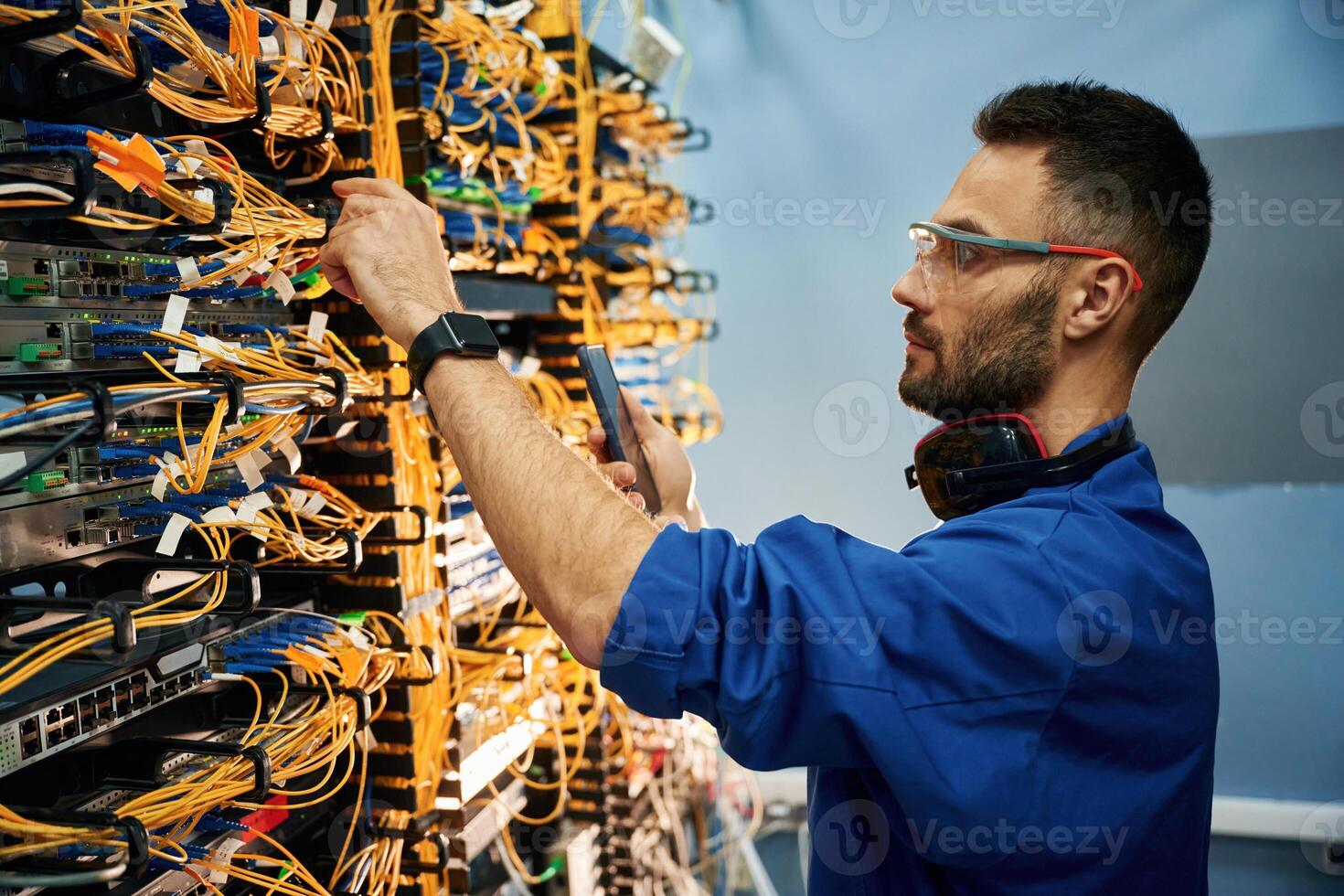 Side view. Young man is ,working with, internet equipment and wires in server room photo