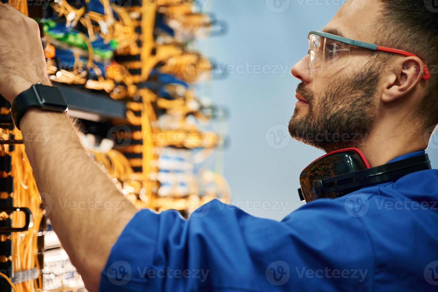 Restoring, the internet connection. Young man is working with equipment and wires in server room photo