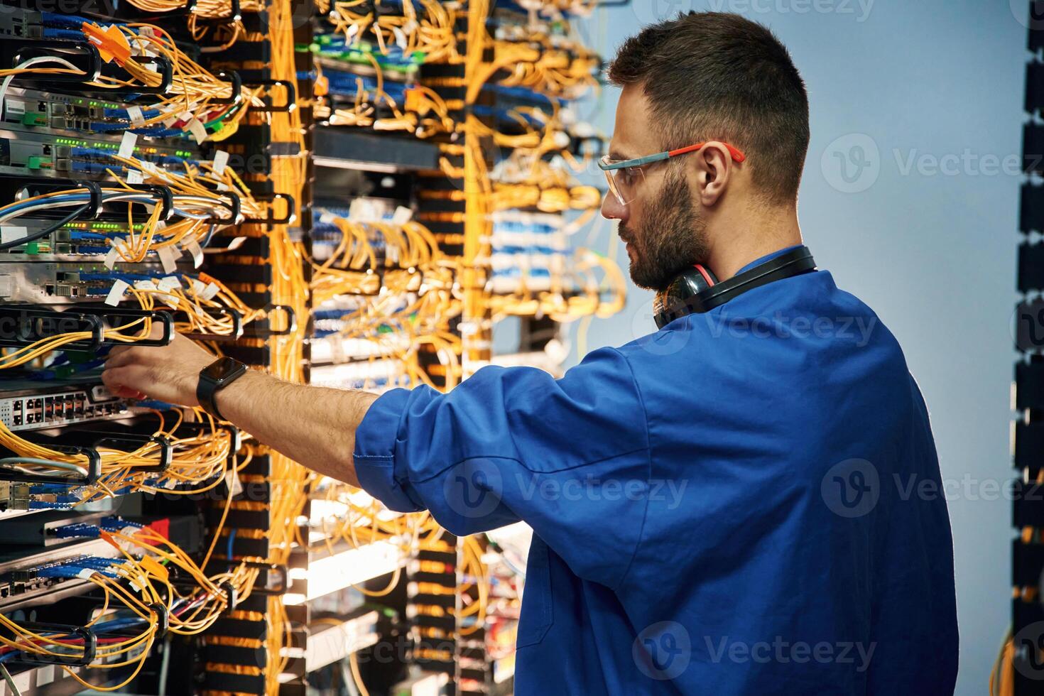 Restoring, the, internet connection. Young man is working with equipment and wires in server room photo