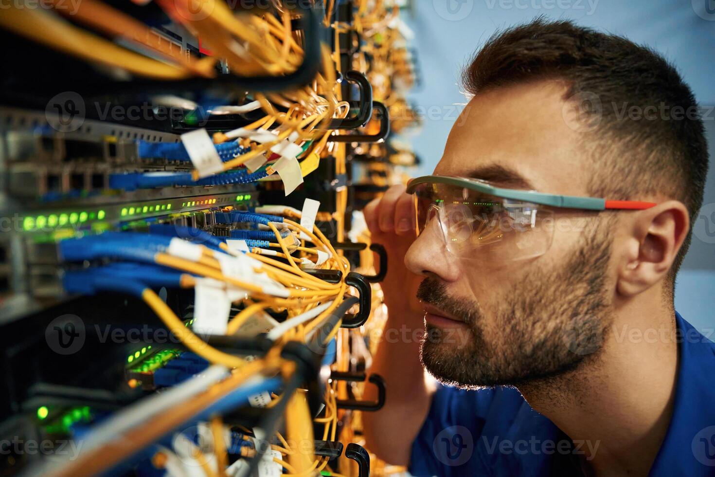 Looking extremely close at cables.,. Young man is working with internet equipment and wires in server room photo