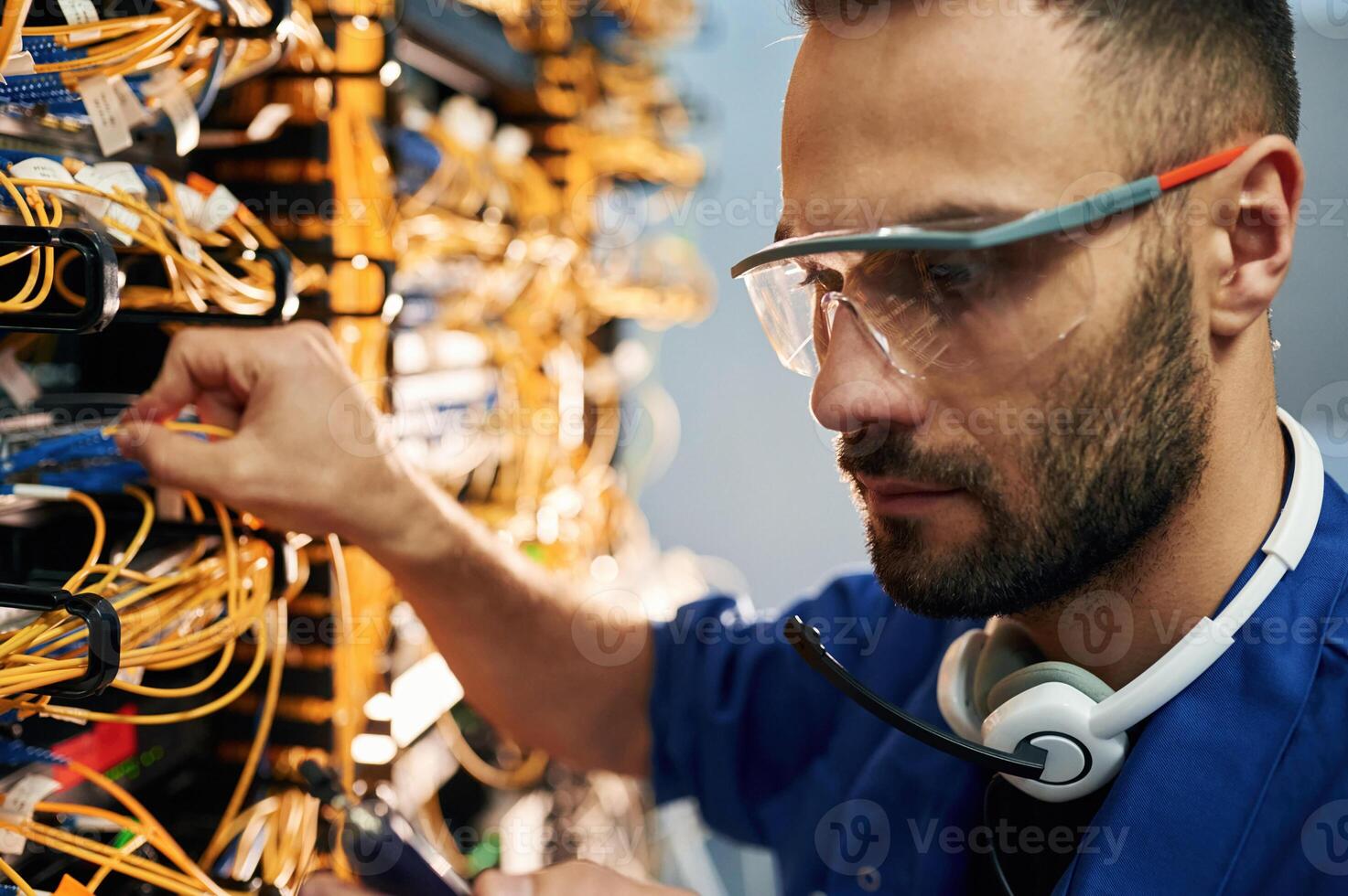 Modern,, technology routing. Young man is working with internet equipment and wires in server room photo
