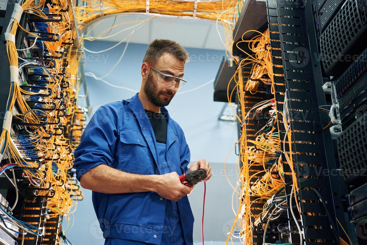 Handsome young, man ,is working with internet equipment and wires in server room photo