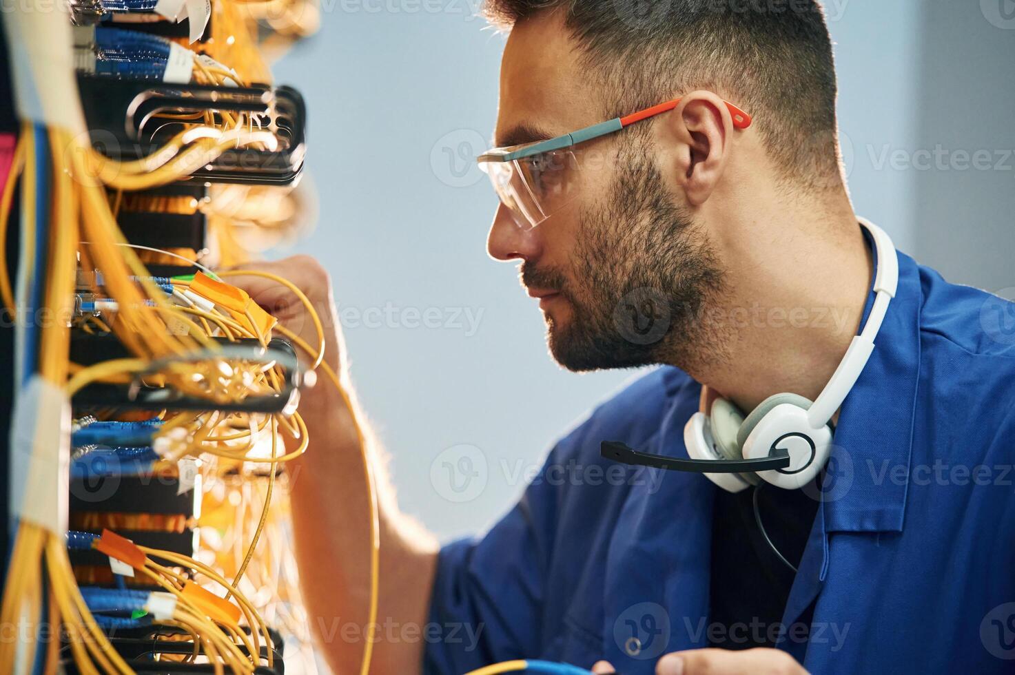 Administrator is busy. Young man is working with internet equipment and wires in server room photo