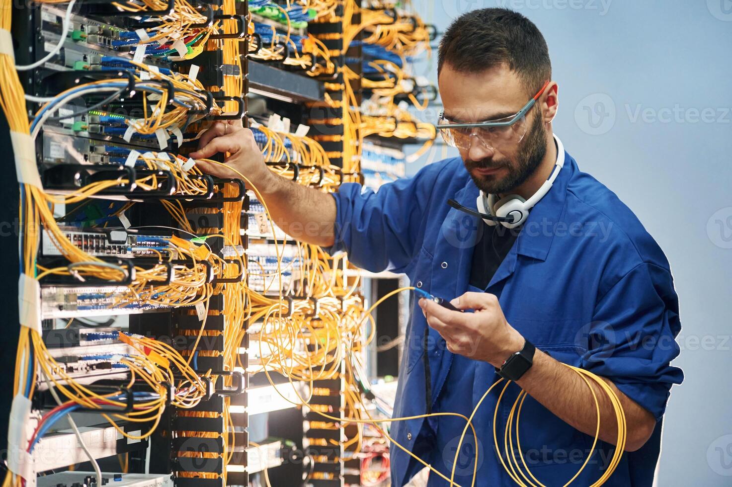 Administrator,, is busy. Young man is working with internet equipment and wires in server room photo