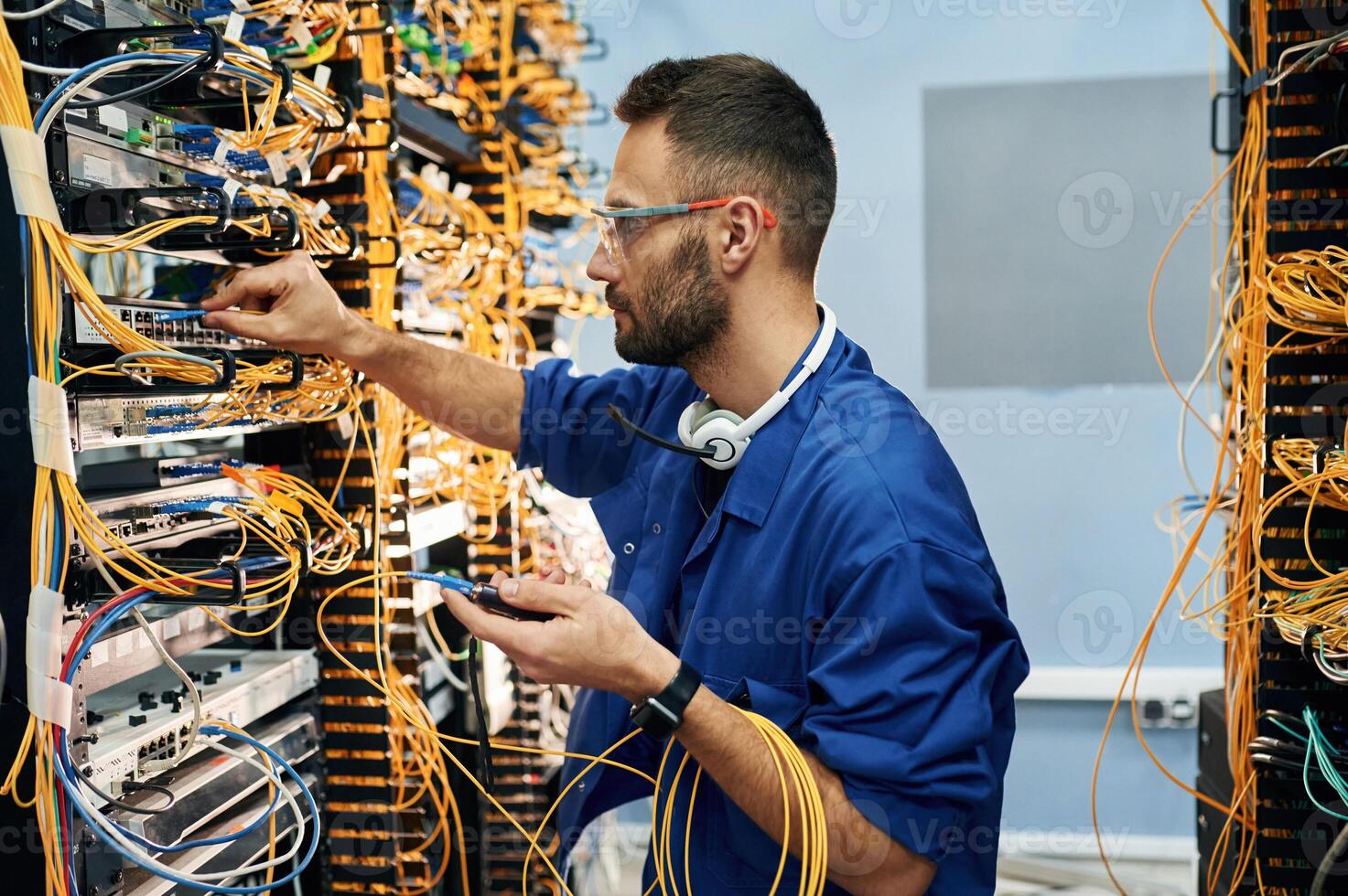 Modern, technology ,routing. Young man is working with internet equipment and wires in server room photo