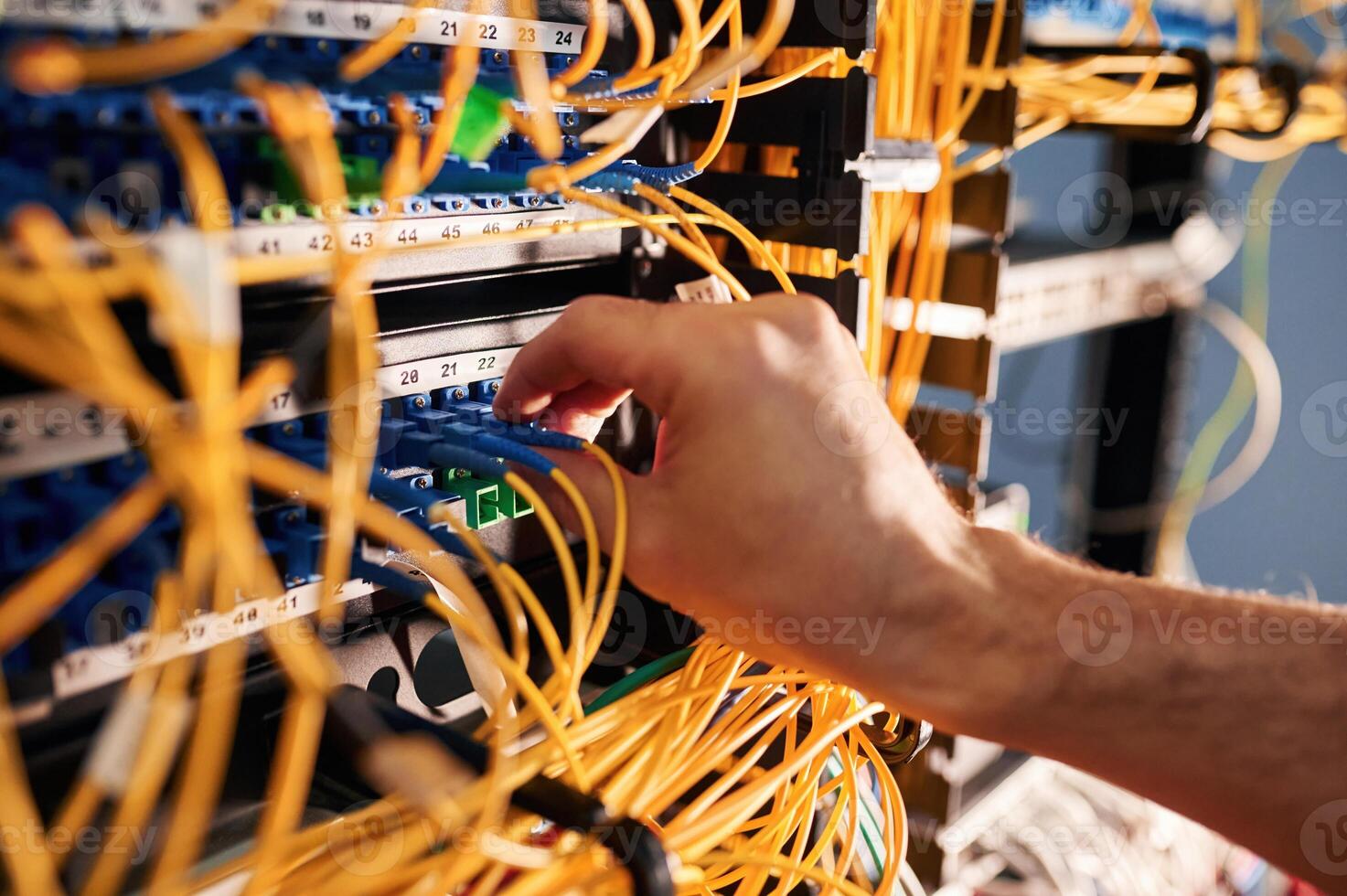 Close ,up view of hand that fixing ,internet. Young man is working with equipment and wires in server room photo