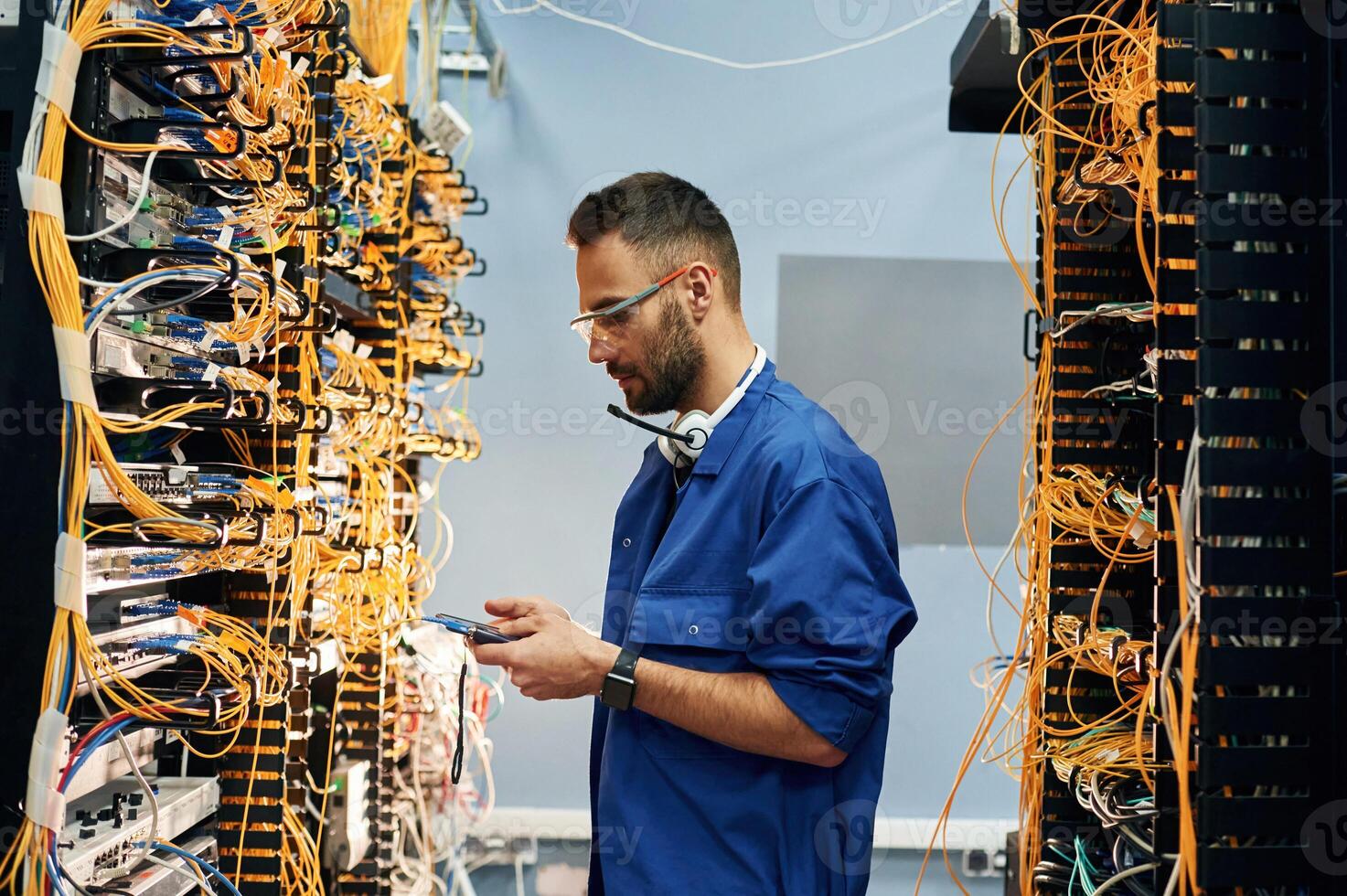 Professional device in hands. Young man is working with internet equipment and wires in server room photo