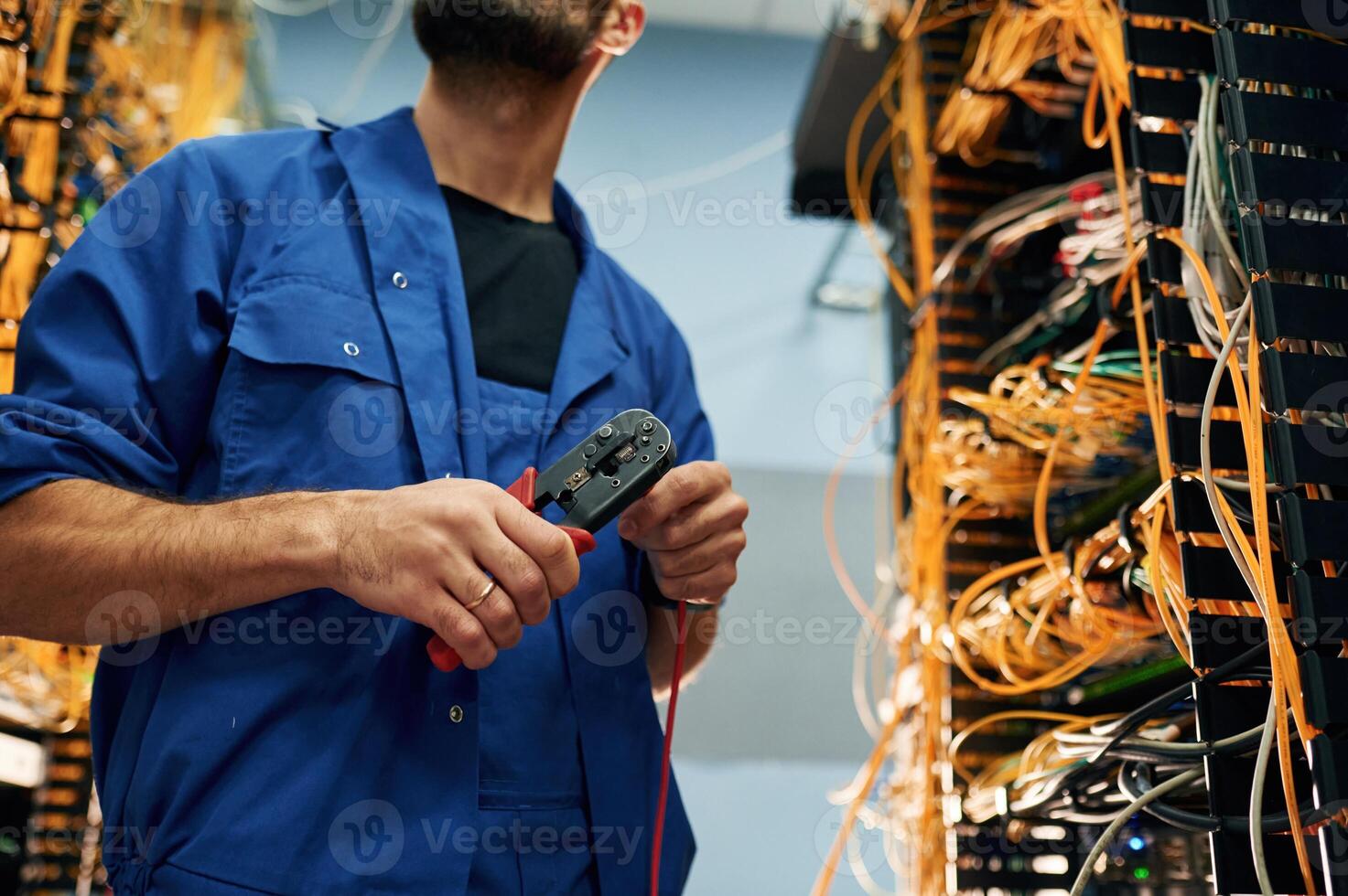 Repairman is, busy, and working with internet equipment and wires in server room photo