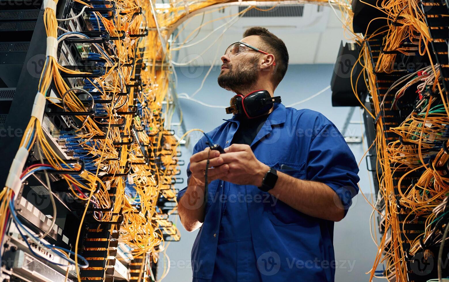 View from ,,below. Young man is working with internet equipment and wires in server room photo