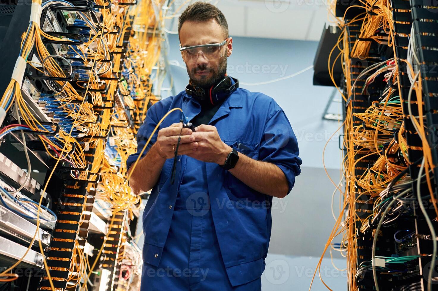 View, from, below. Young man is working with internet equipment and wires in server room photo