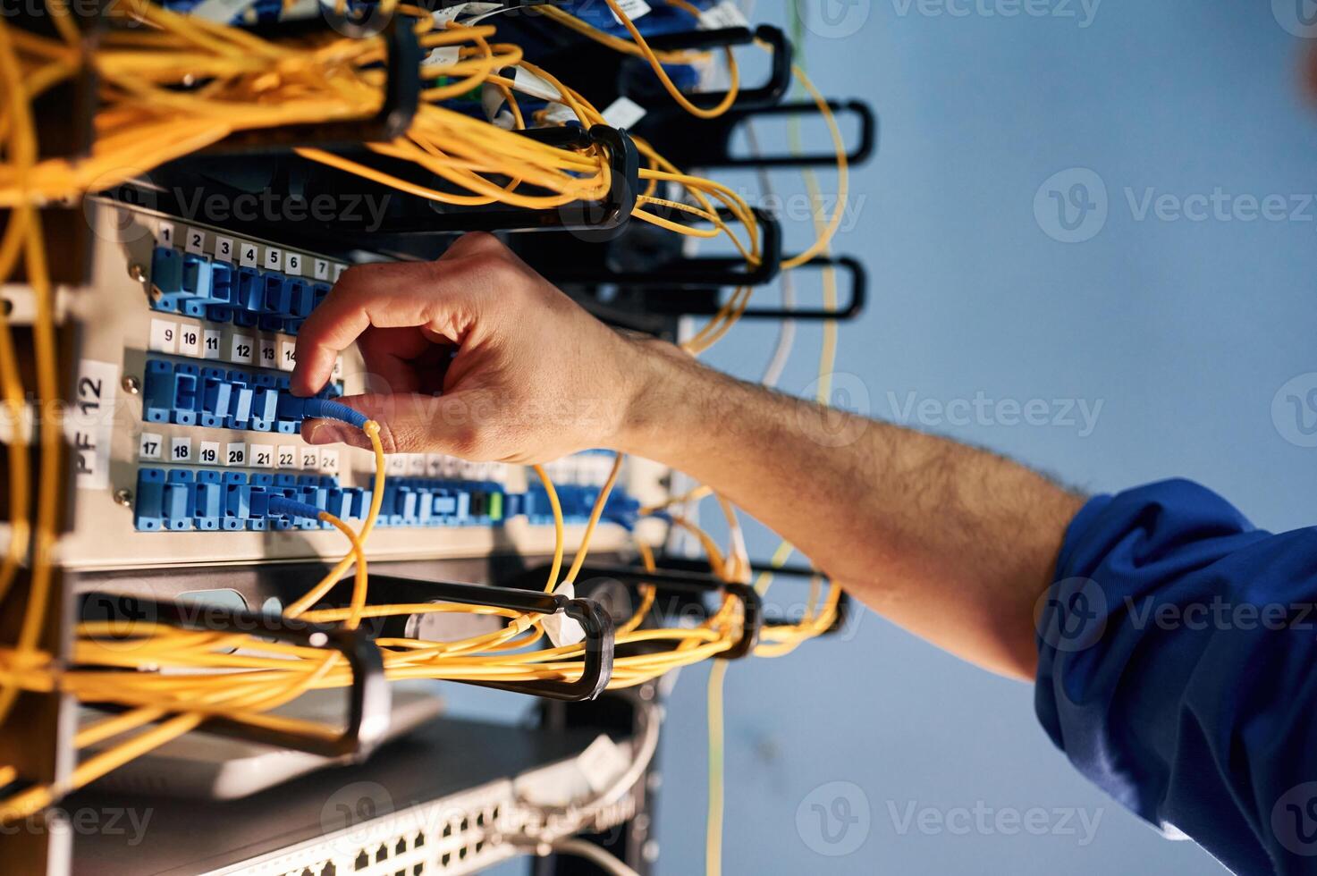 Close up view of hand that, fixing internet. Young man is working with equipment and wires in server room photo