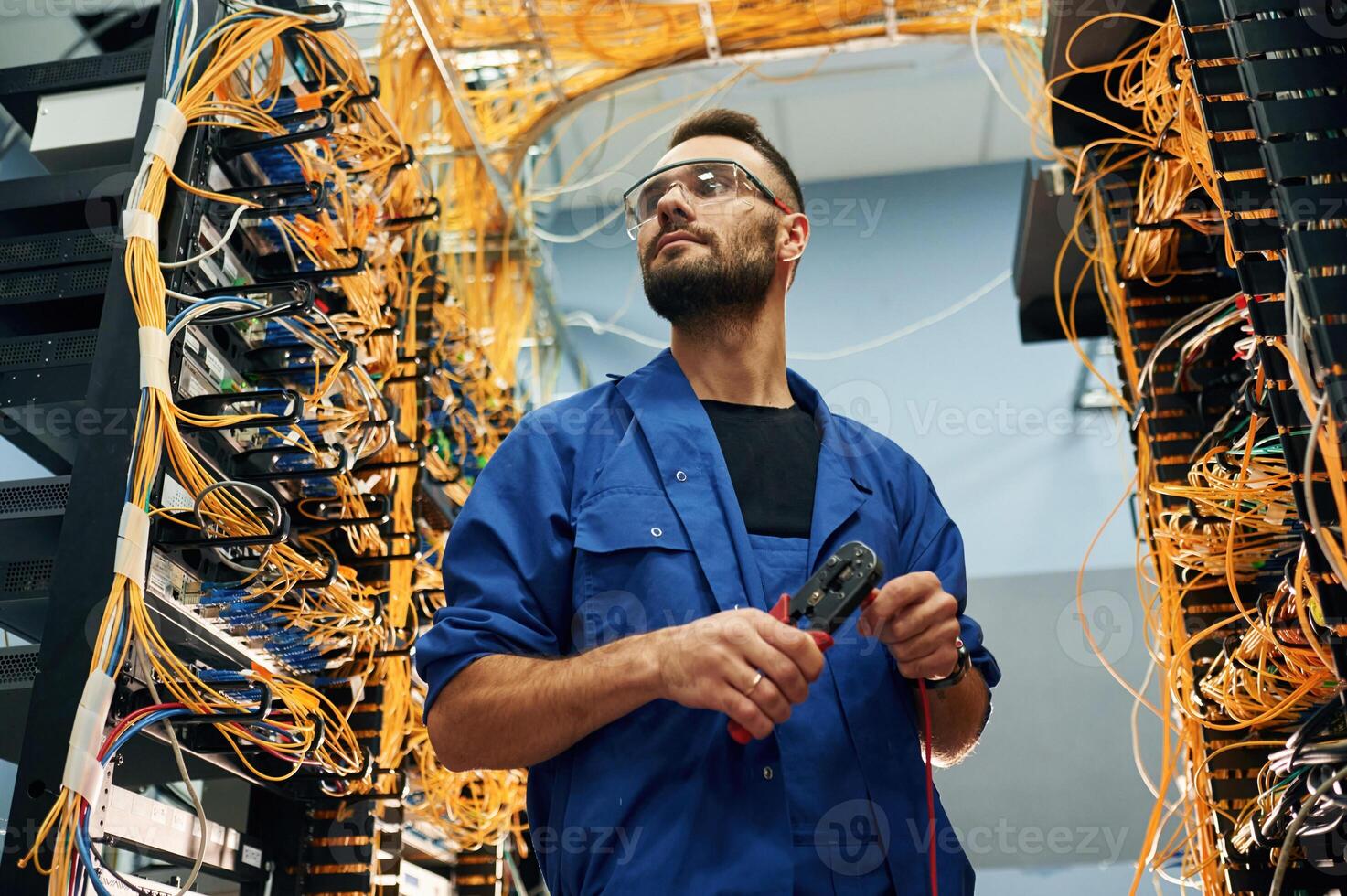 Administrator is busy,,. Young man is working with internet equipment and wires in server room photo