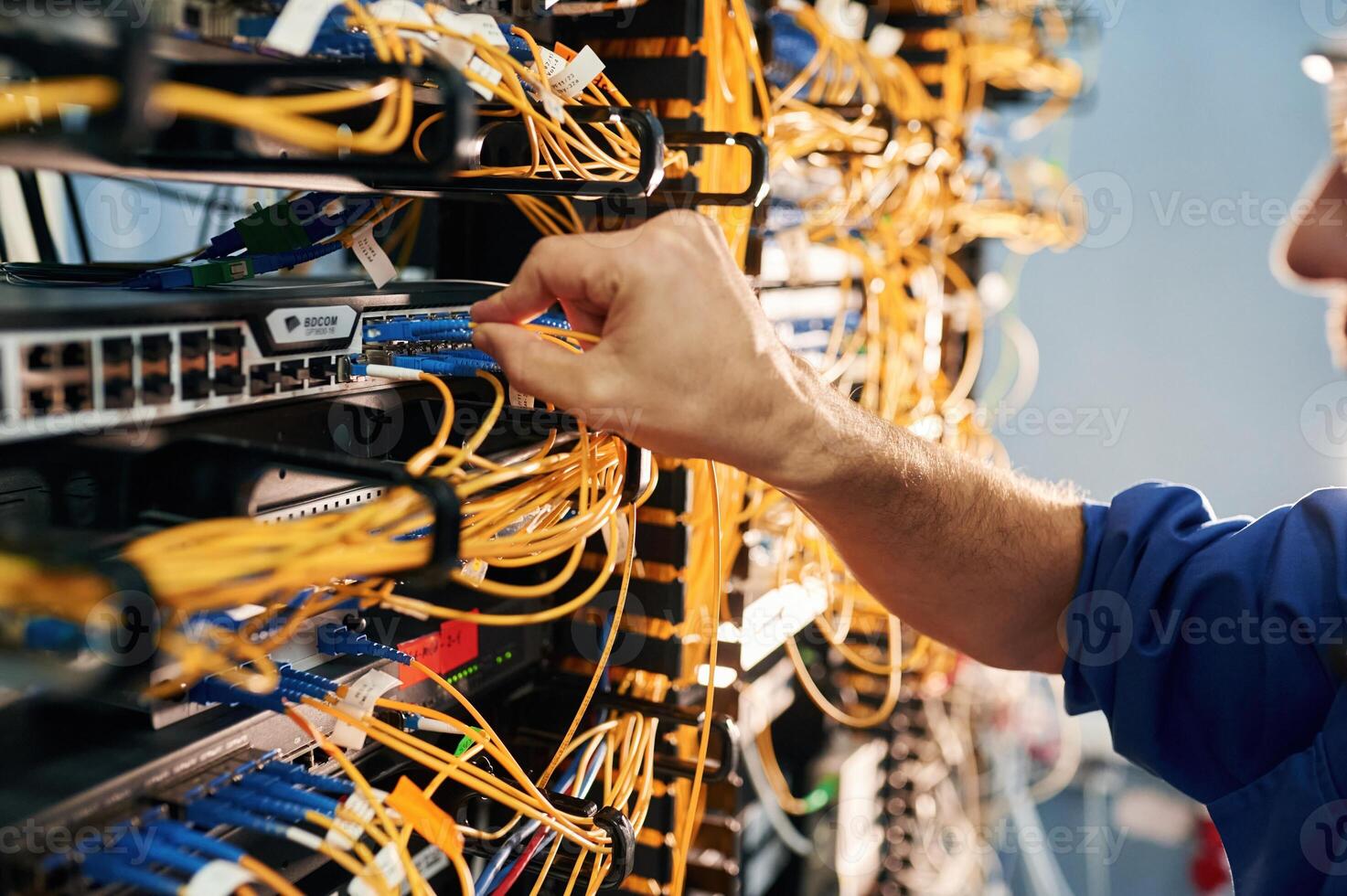 Close up ,view, of hand that fixing internet. Young man is working with equipment and wires in server room photo
