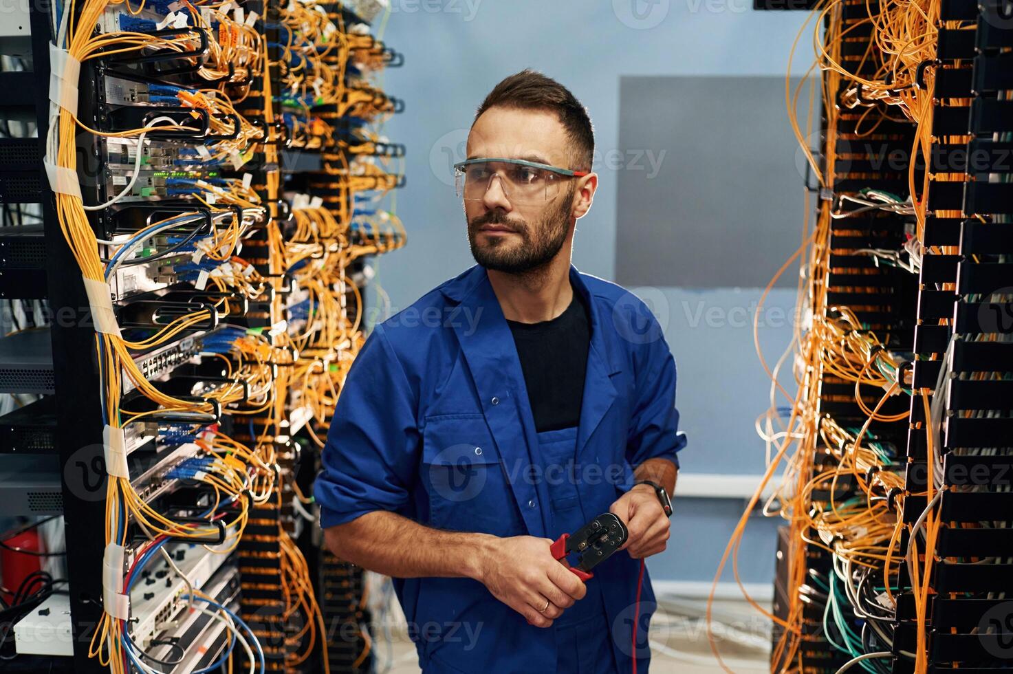 Administrator is ,,busy. Young man is working with internet equipment and wires in server room photo