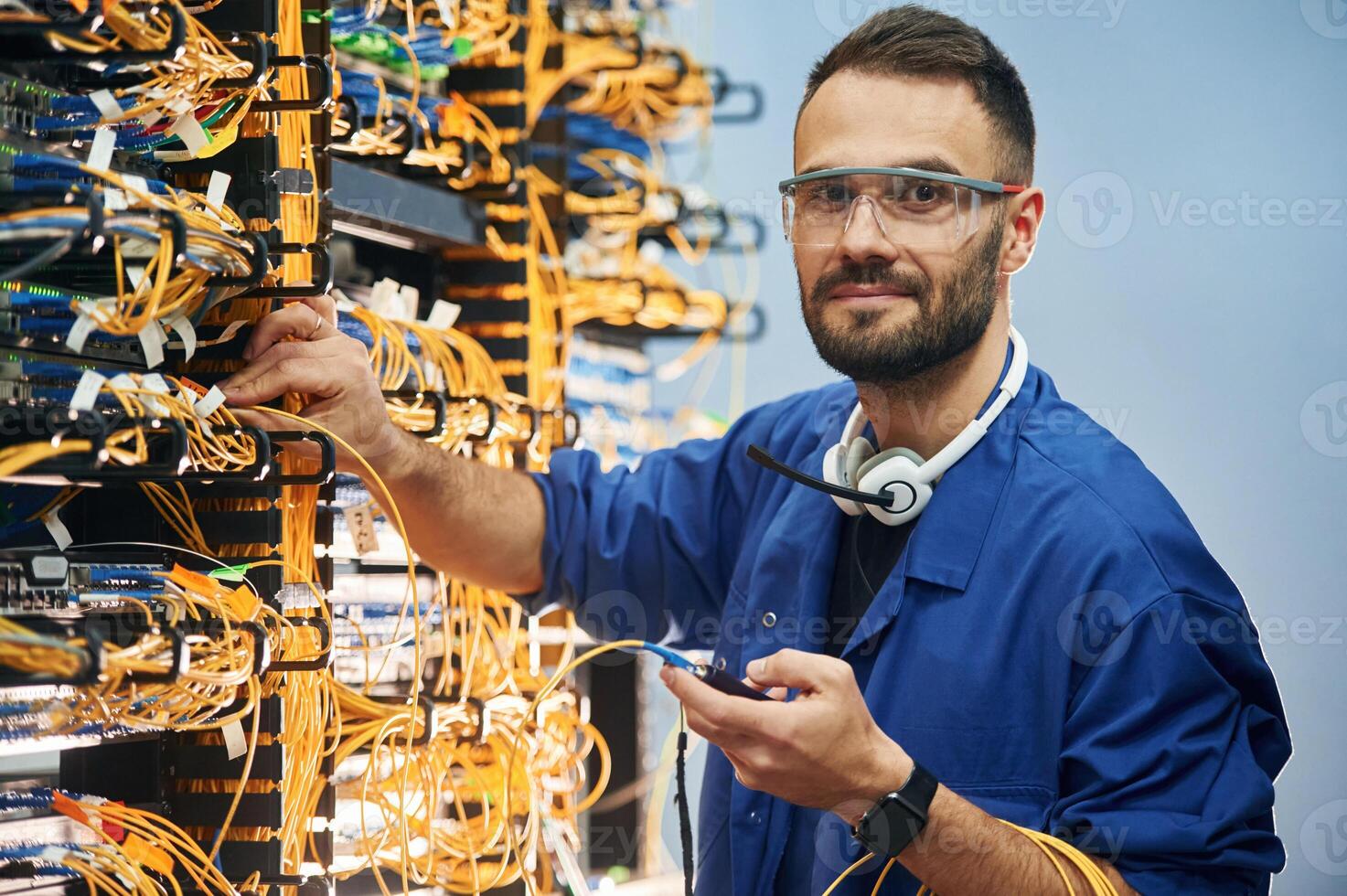 Checking ,signal by ,device. Young man is working with internet equipment and wires in server room photo