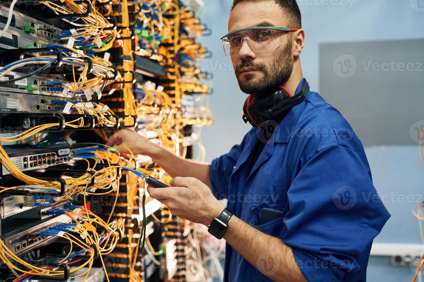 Signa,l stability measured by device. Young man is working with internet equipment and wires in server room photo