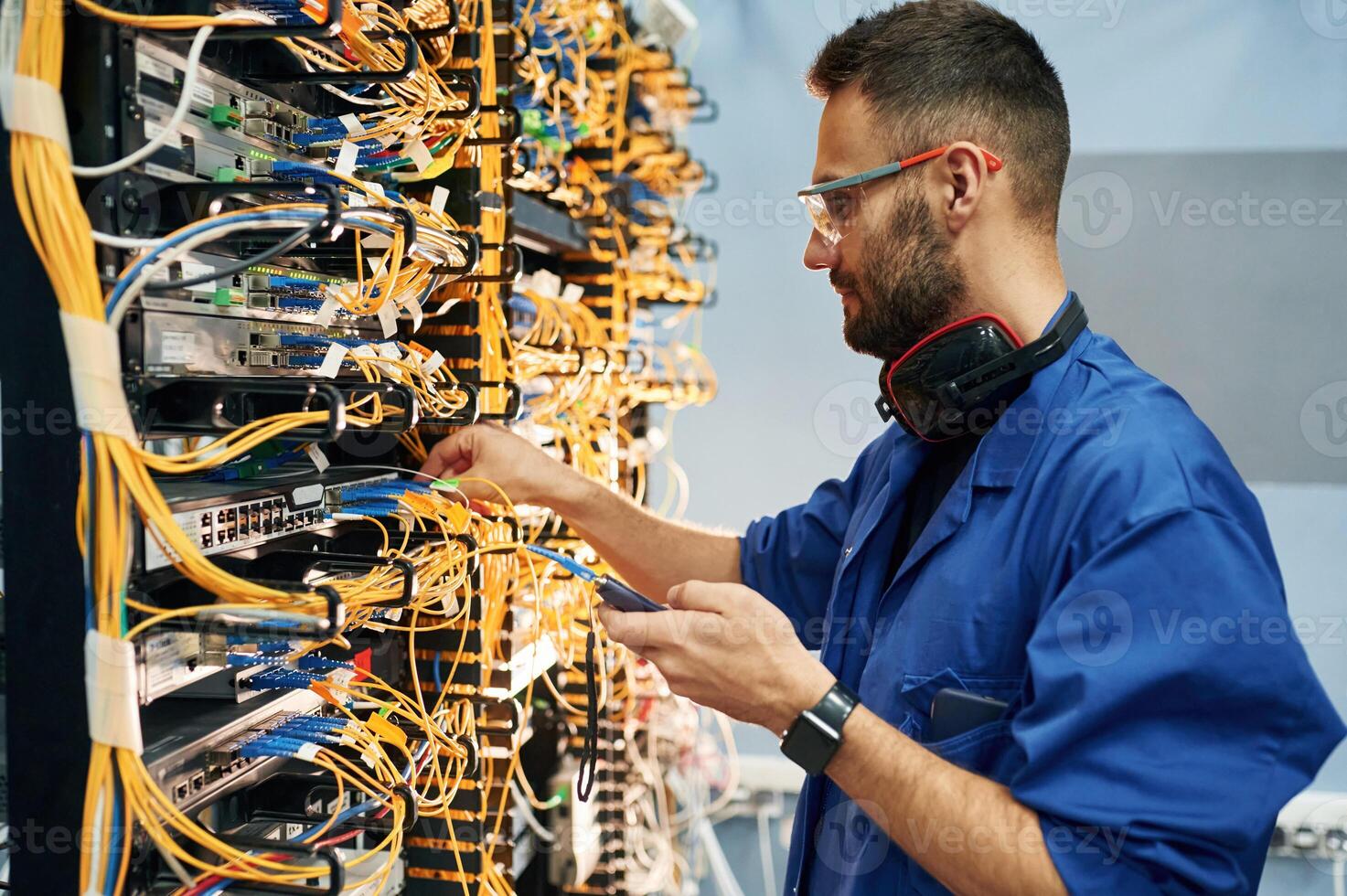 Signal ,stability measured by device. Young man is working with internet equipment and wires in server room photo