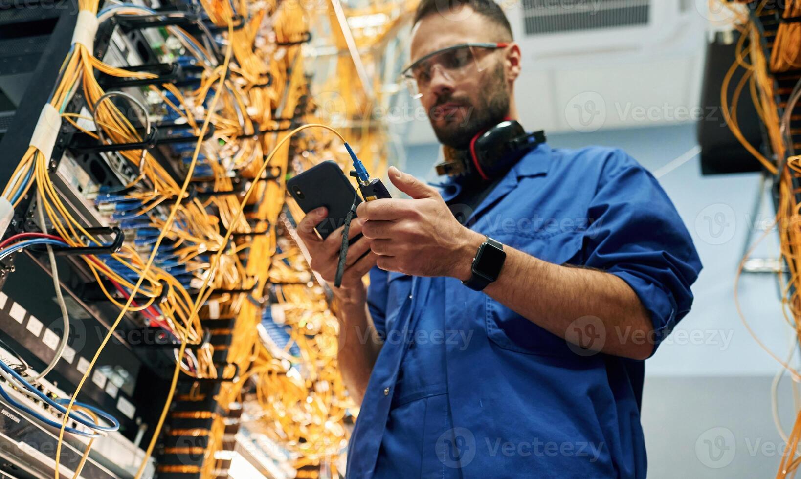 View, from below. Young man is working with internet equipment and wires in server room photo