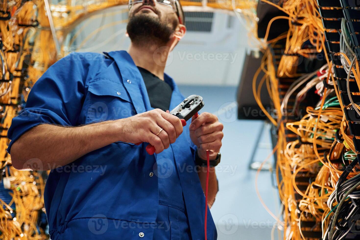 Busy,, by cutting the wire. Young man is working with internet equipment in server room photo