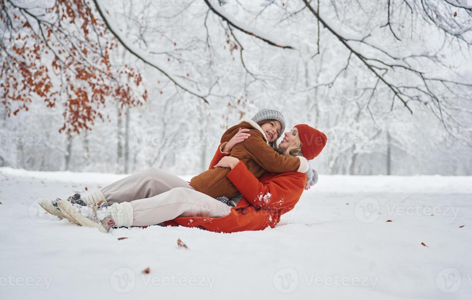 Lying down on the snow. Mother, and ,her daughter is on the winter meadow and forest photo