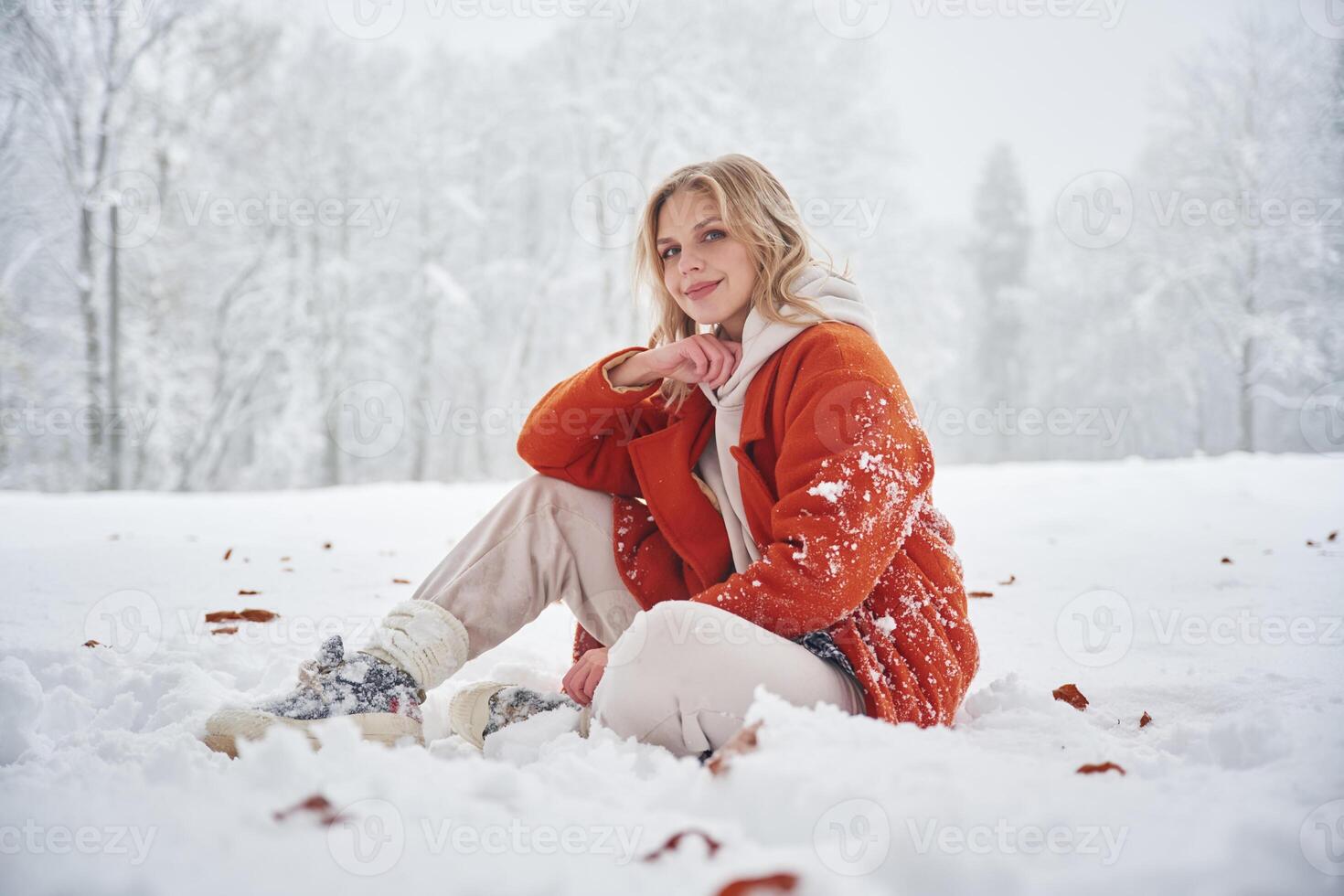 Beautiful ,,woman in red warm jacket is sitting on the winter field photo