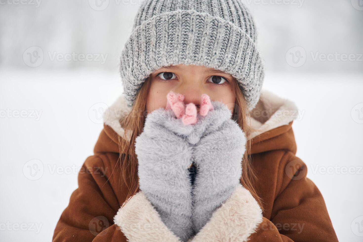 Shocked,, covering face with hands. Portrait of cute little girl on the winter field photo