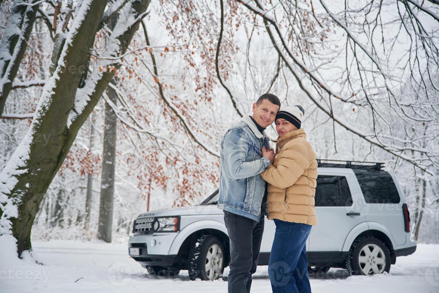 Standing, and posing. Beautiful, couple are near the car in the winter forest photo