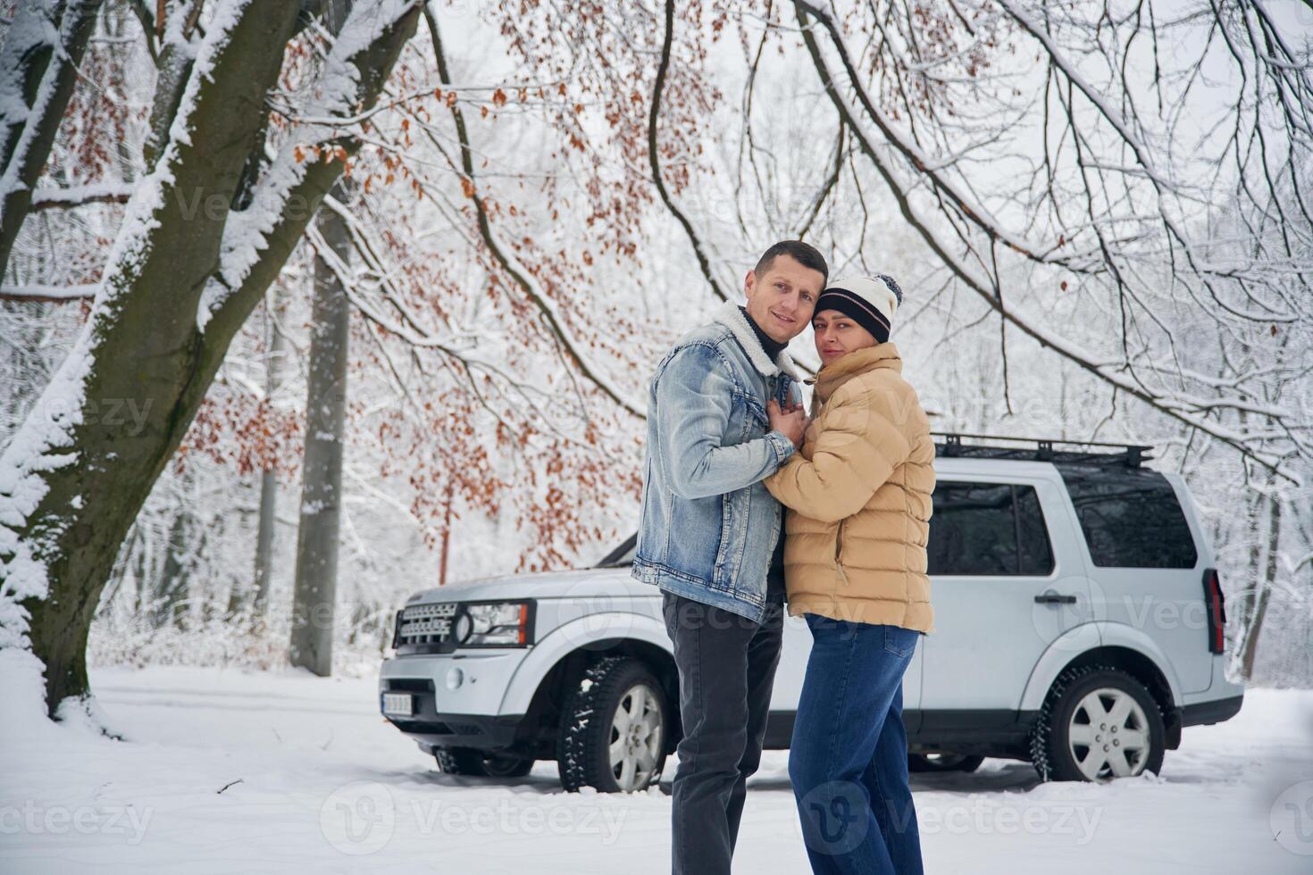 Embracing each other.. Beautiful ,couple standing near the car in the winter forest photo