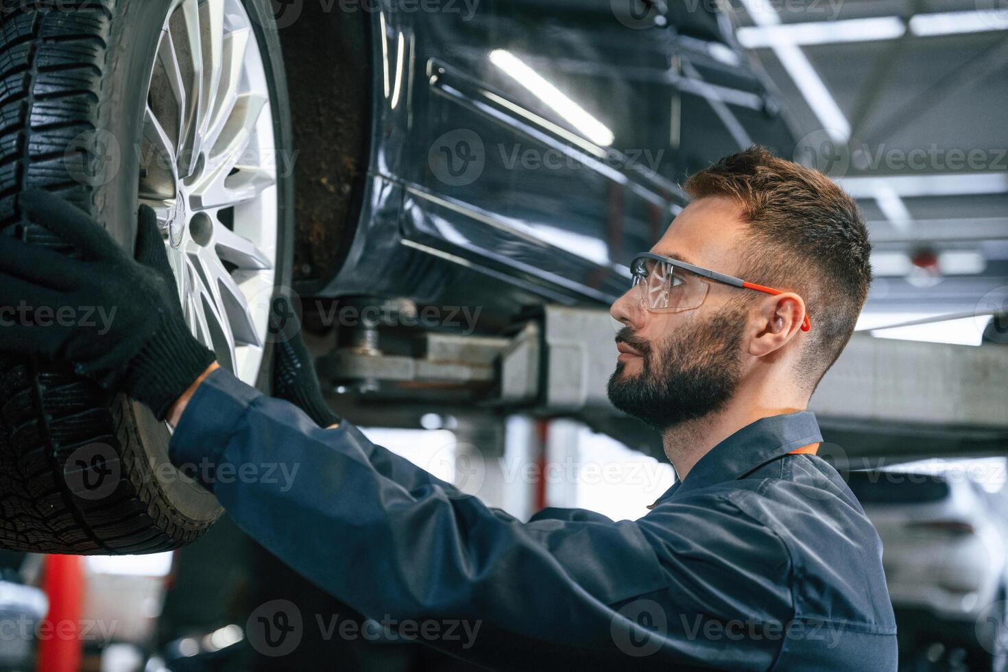 Fixing,, broken vehicle. Car repairman is in the garage with automobile photo