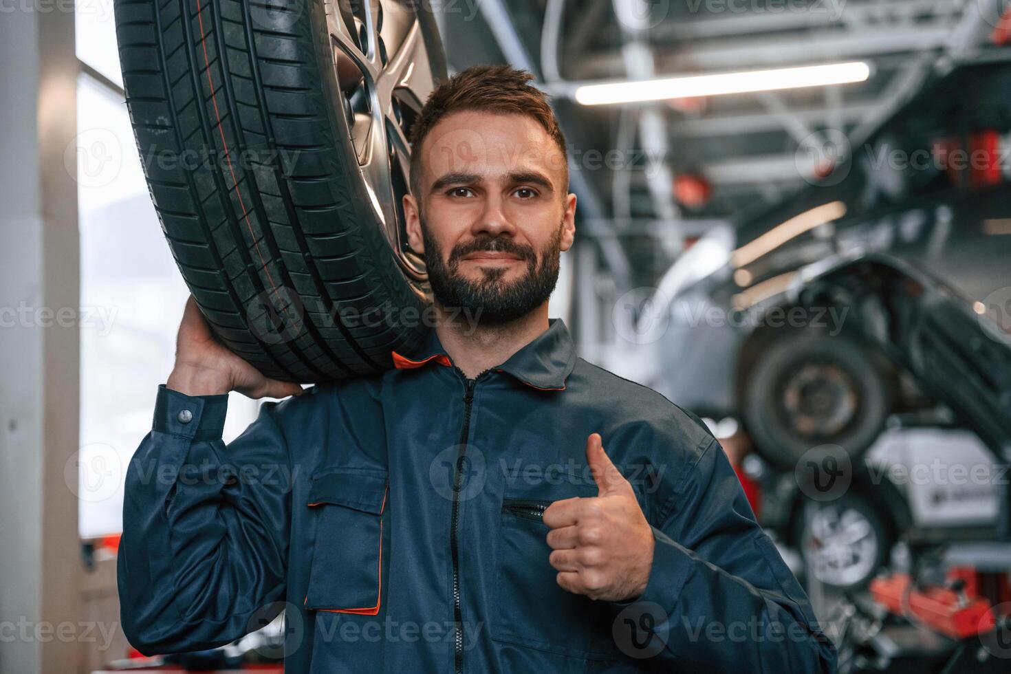 With, brand new tire. Car repairman is in the garage with automobile photo