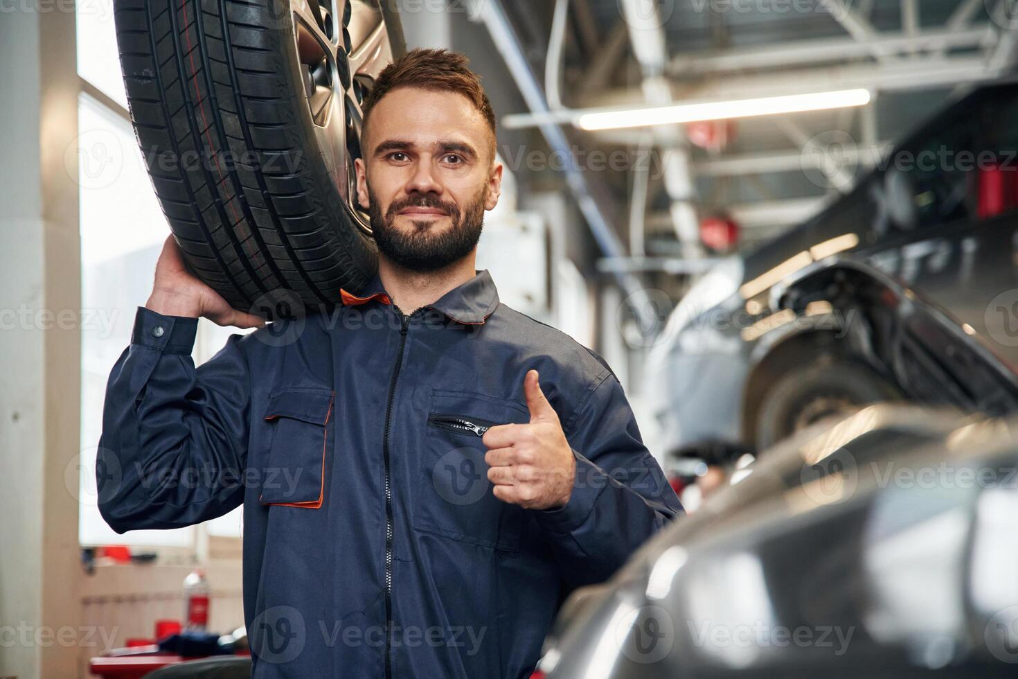 With ,brand new tire. Car repairman is in the garage with automobile photo