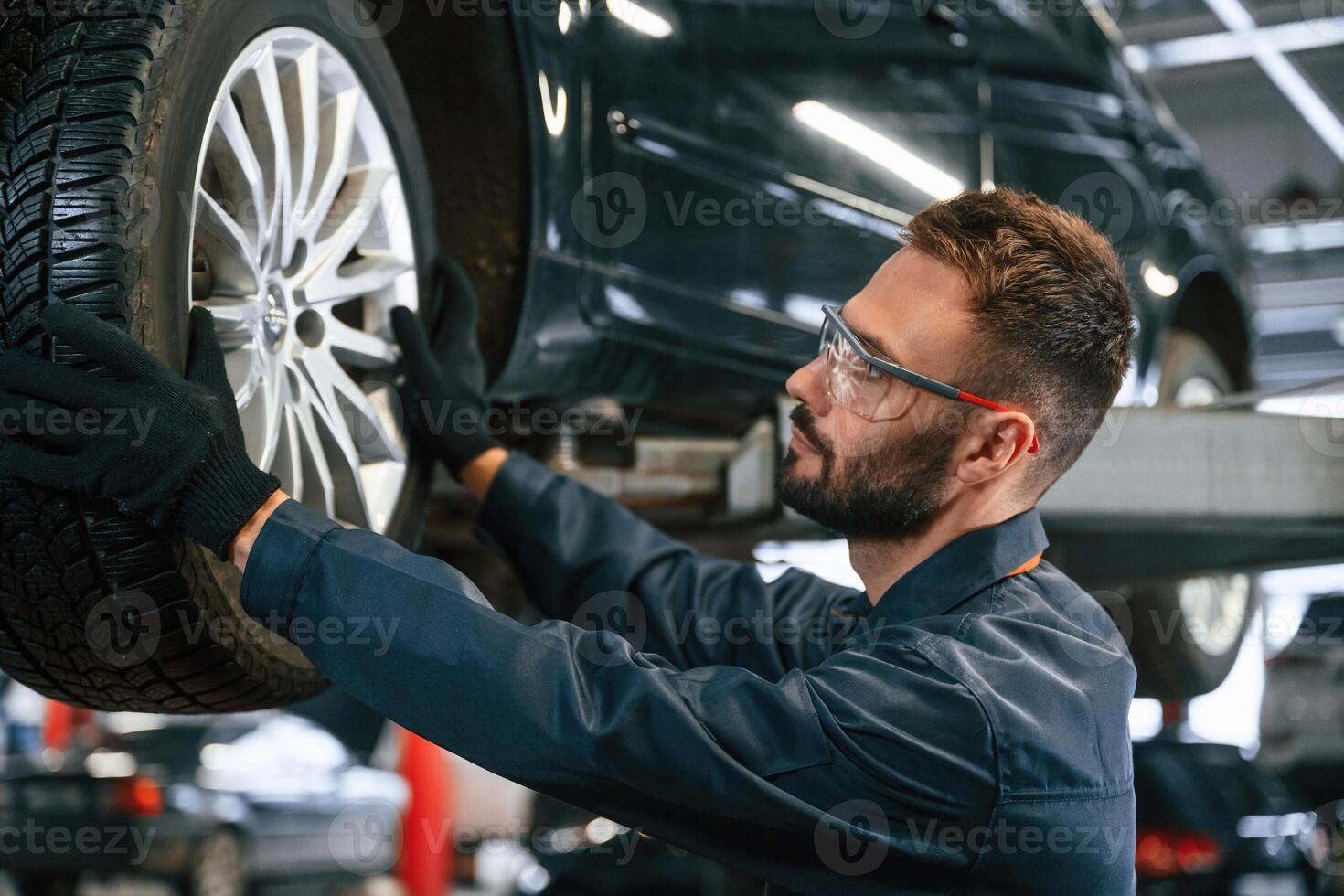 Fixing, broken vehicle. Car repairman is in the garage with automobile photo