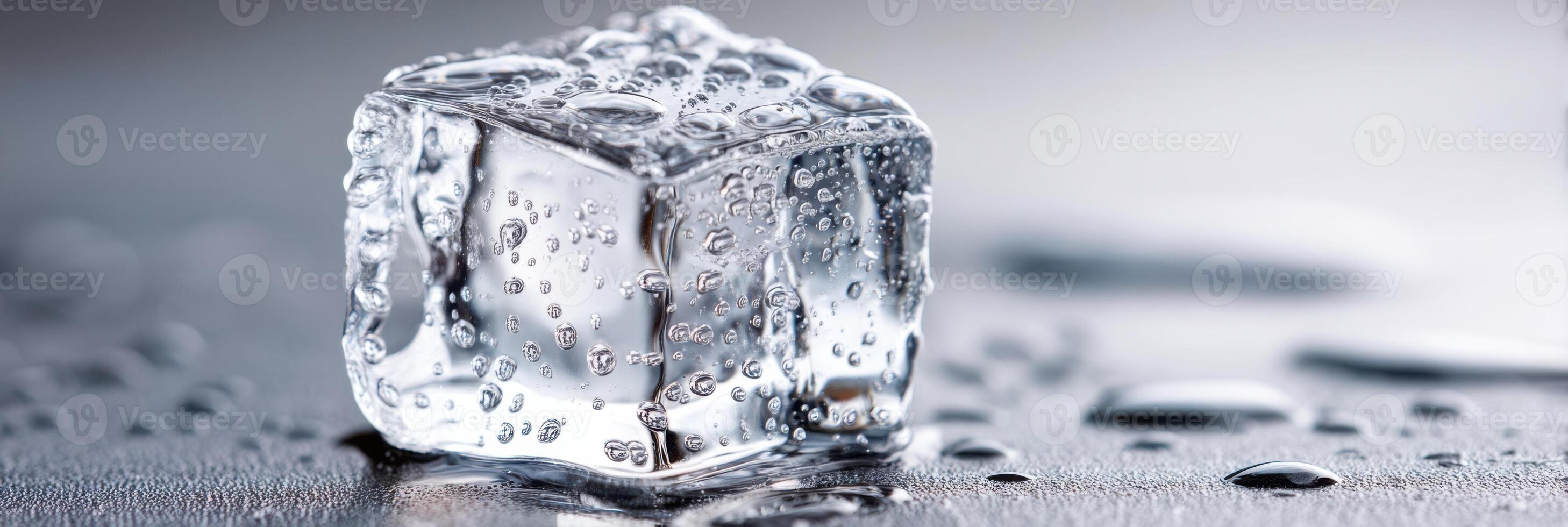 Perfectly shaped ice cube melting on a reflective surface with water drops photo