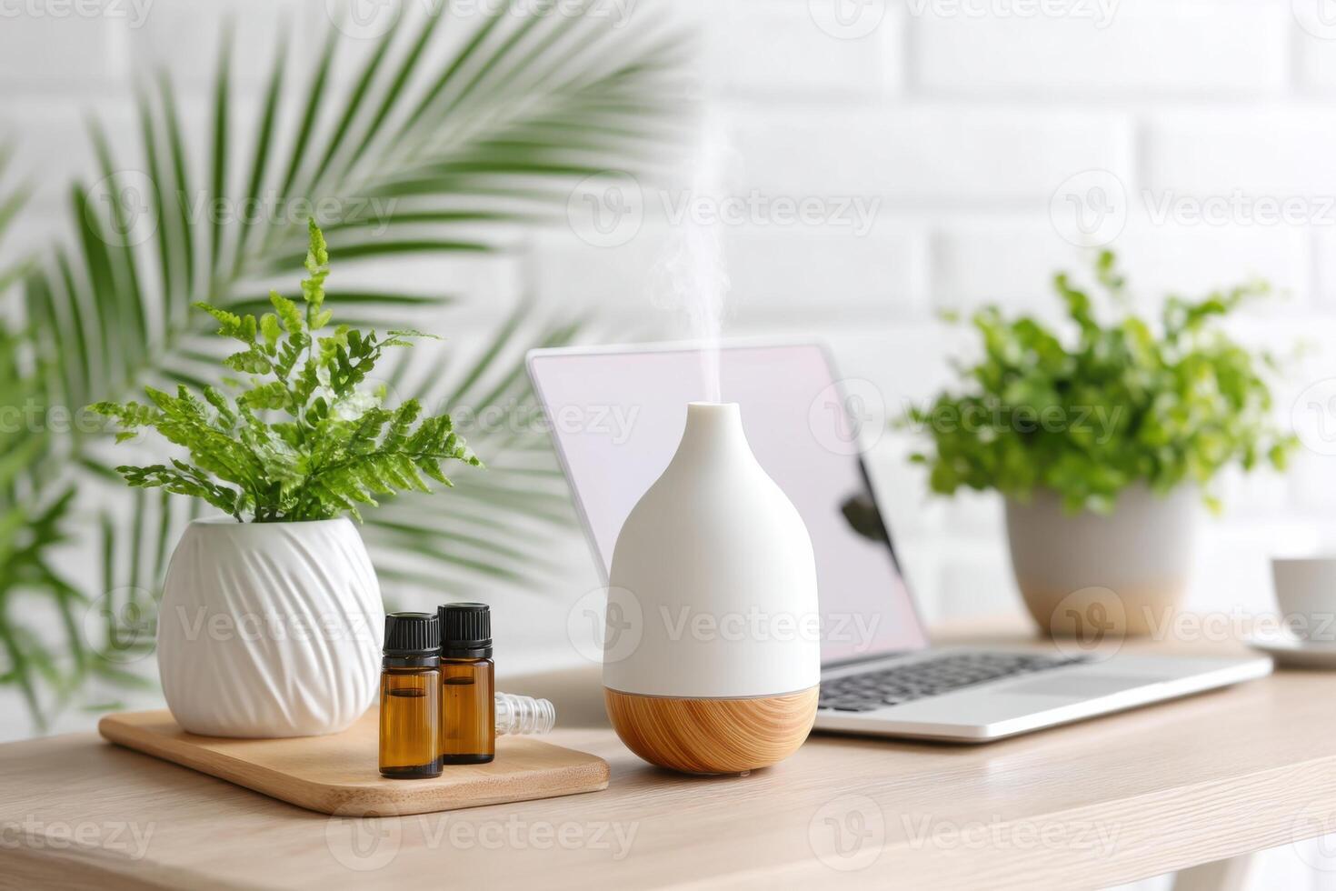 Aromatherapy diffuser with essential oils, plants, and laptop on a wooden table in a bright, modern workspace, wellness and relaxation concept photo