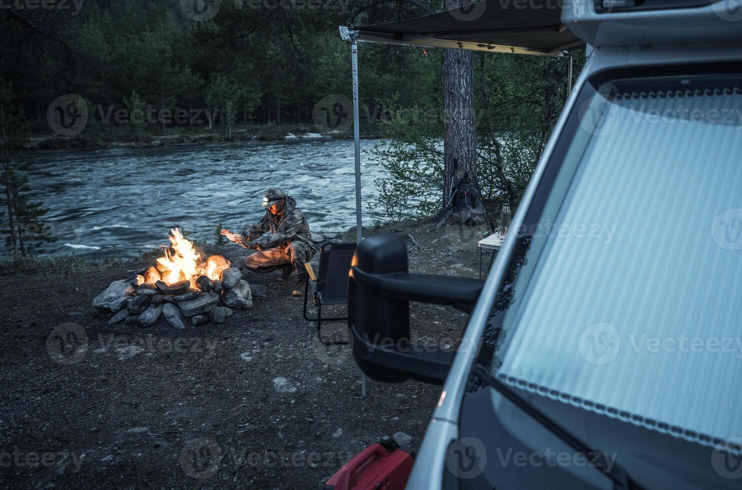 Fisherman Enjoys Quiet Evening by River With Campfire photo