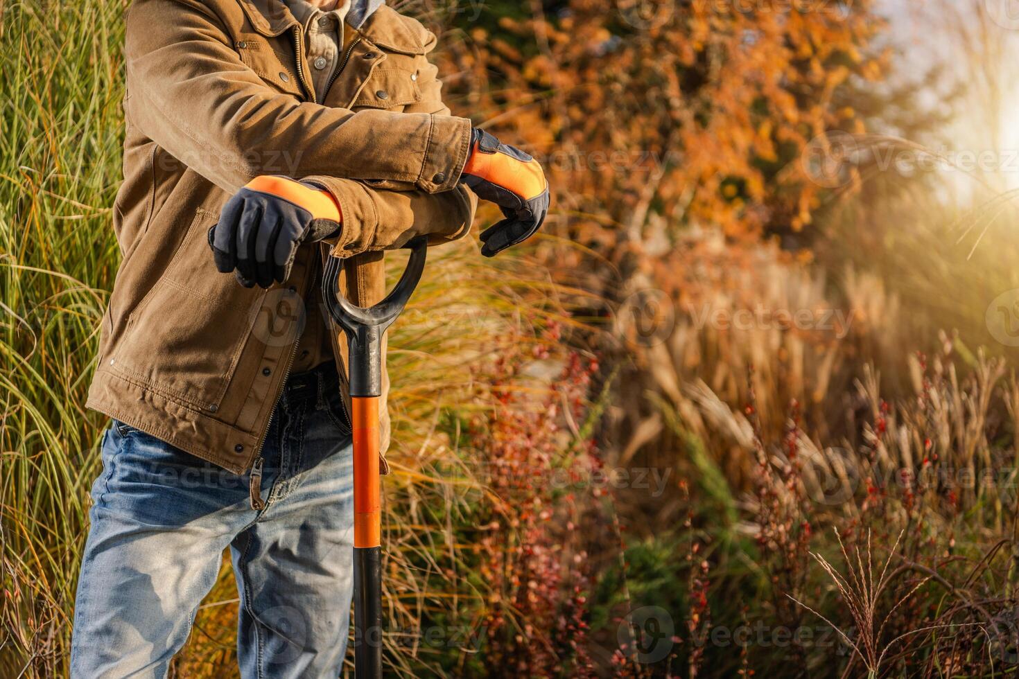 Gardener Leaning on Shovel in a Vibrant Autumn Garden Setting photo