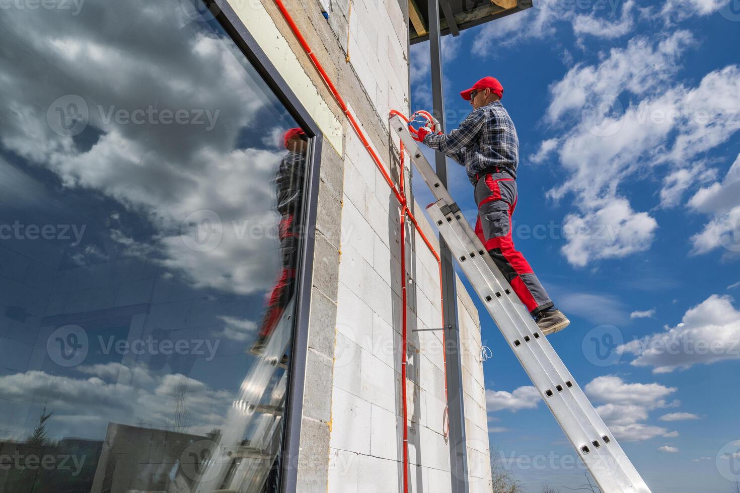 Worker on Ladder Installing Exterior Fixtures on Building photo