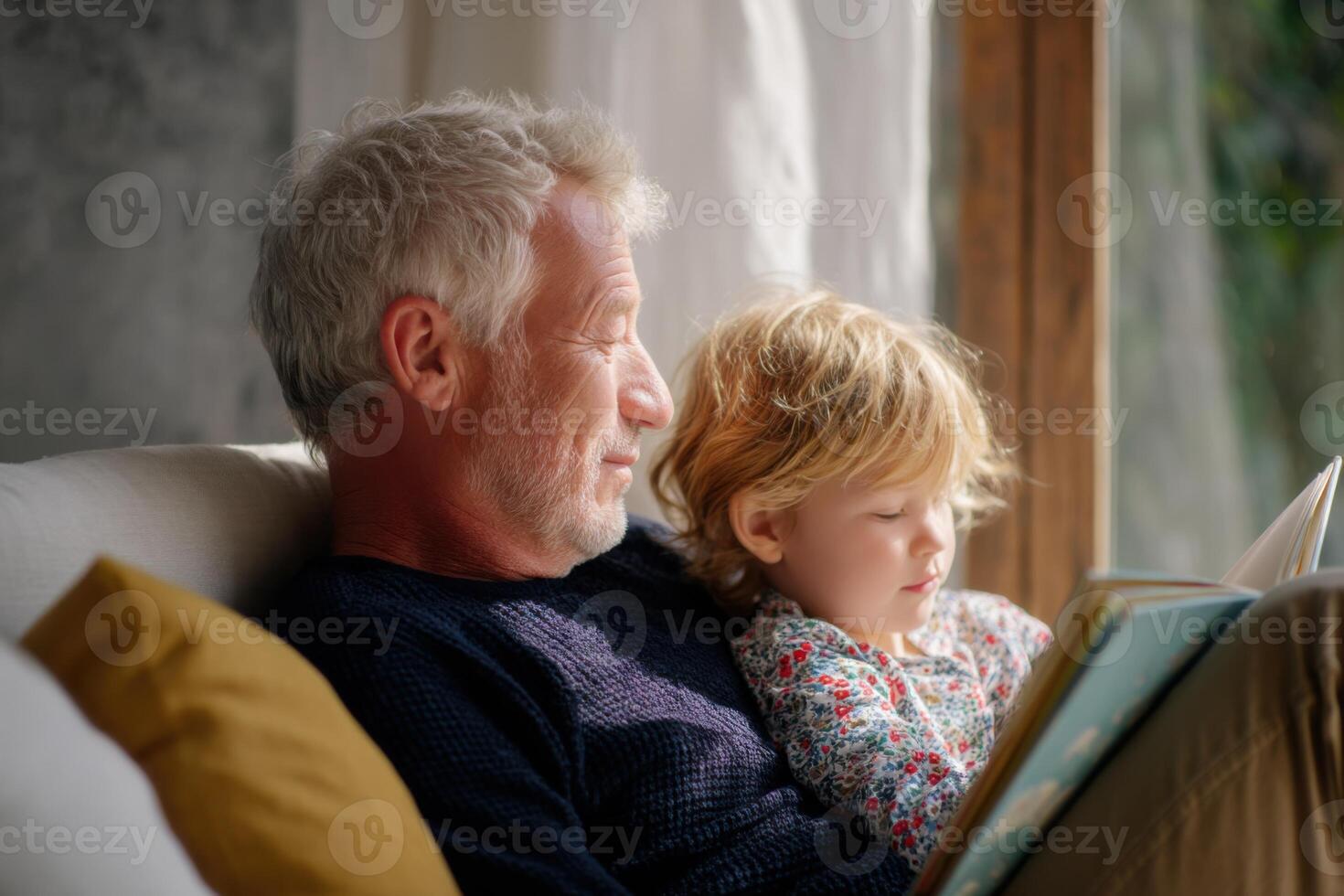 Grandfather reading a book to grandchild on sofa at home photo
