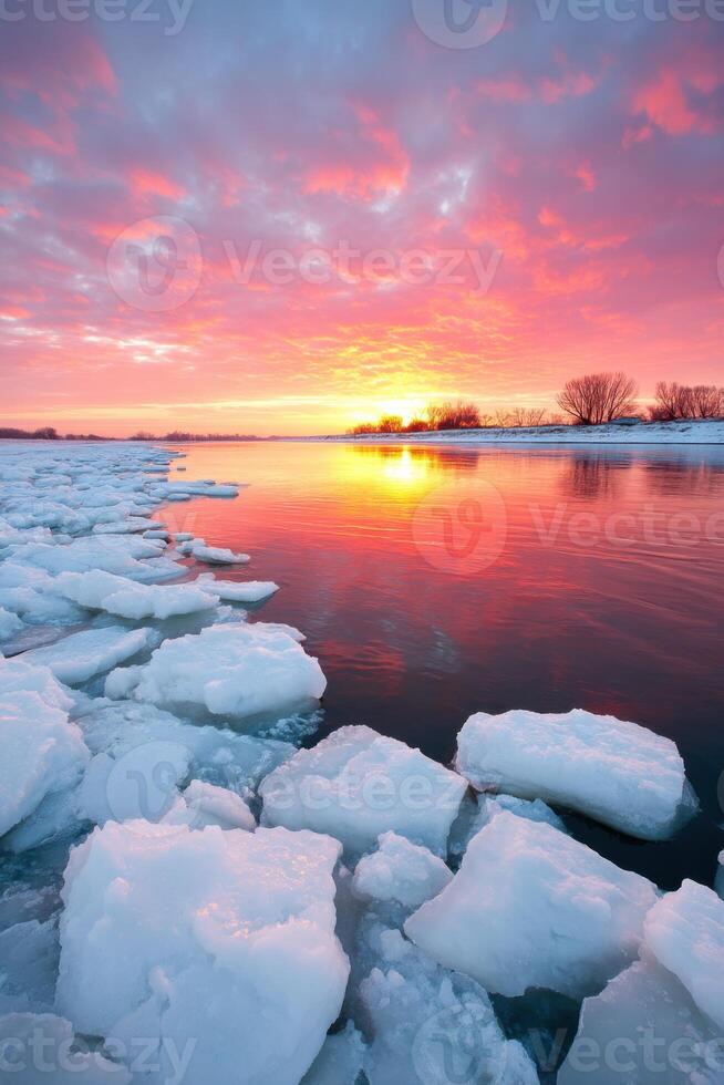 Vibrant sunset over icy river landscape with colorful clouds reflecting on water surface creating a serene winter atmosphere nature concept photo